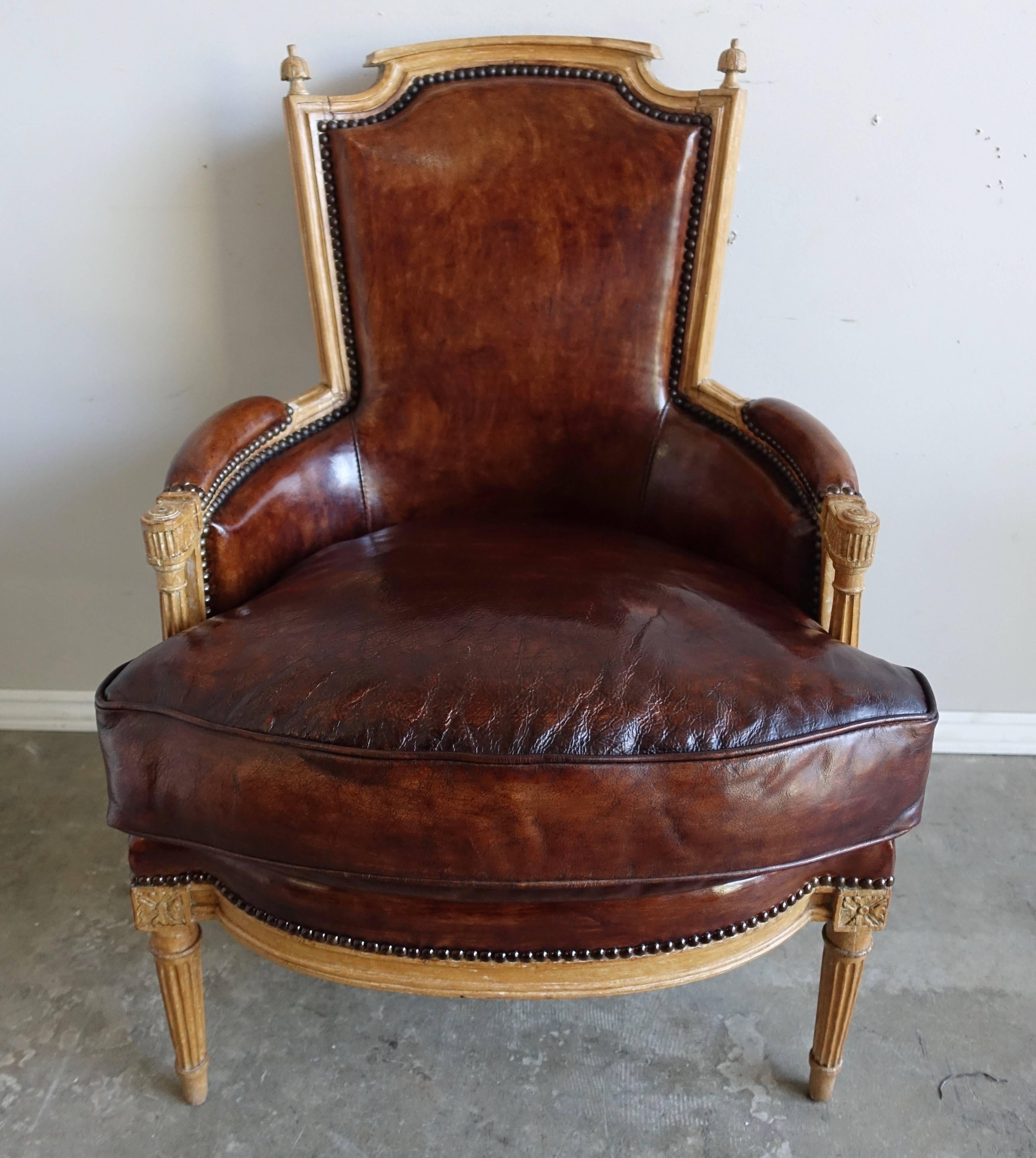 Pair of Louis XVI style leather upholstered armchairs with a bleached natural walnut finish. The chairs stand on four fluted straight legs. Loose down filled cushion.