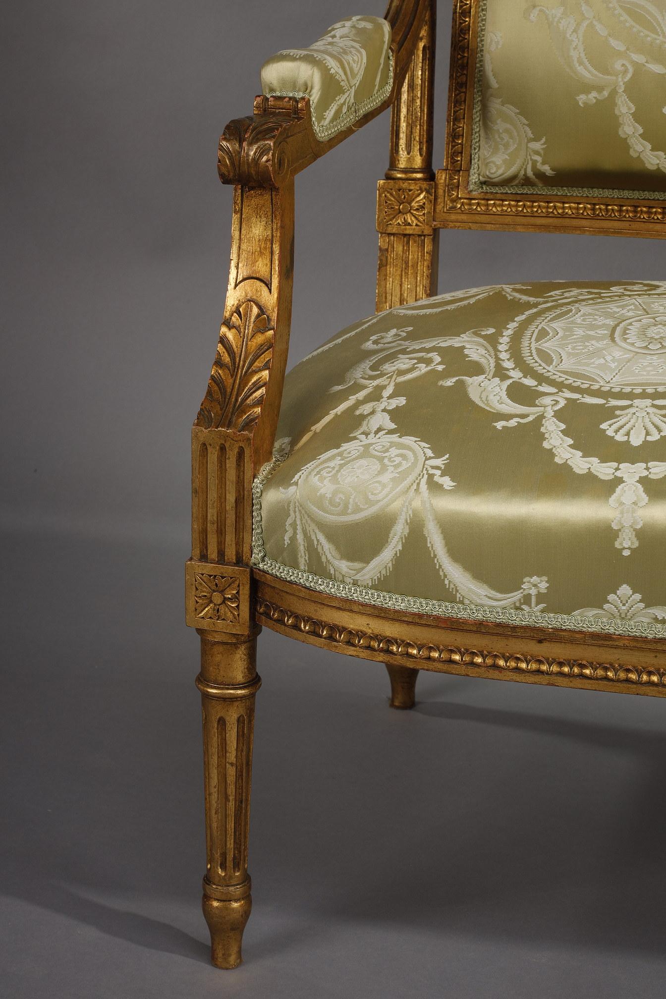 Louis XVI style living room ensemble in gilded wood with a sofa, two armchairs and two chairs. The posts are made of detached fluted columns and topped by dice with flowers and small feathers sculptures. The base is composed of fluted and tapered