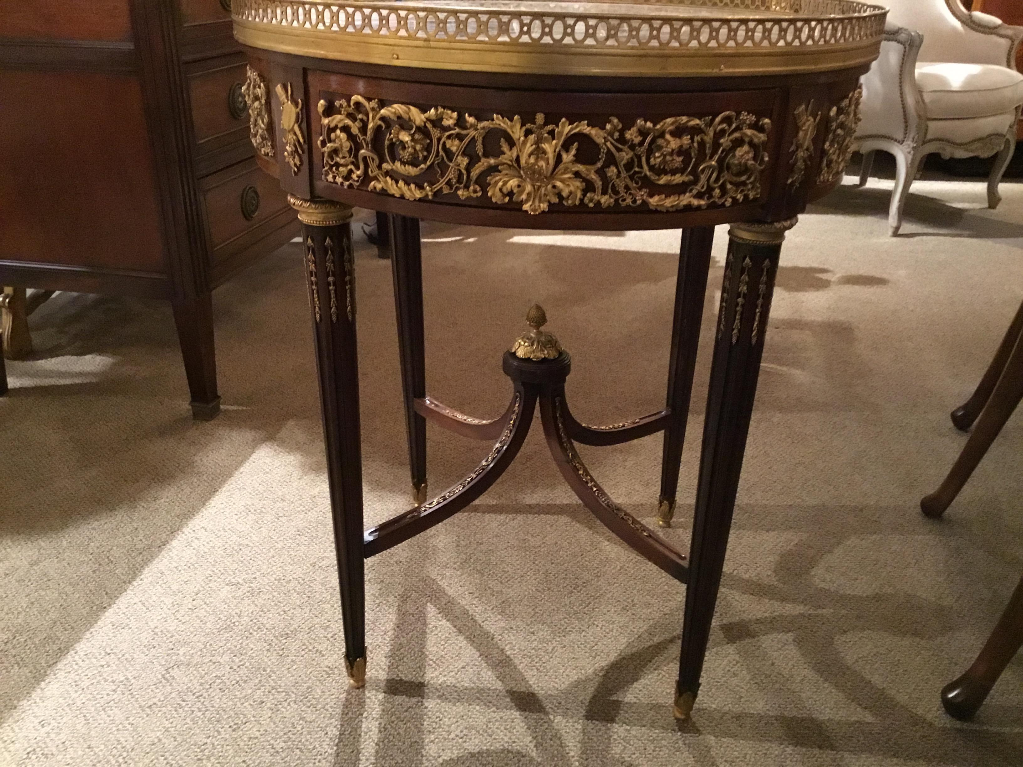 Circular marble top within a full pierced brass gallery, above a conforming
Frieze, paneled and fitted with a single drawer, each panel with an applied
Scrolling foliate ormolu mount, raised on fluted tapering circular legs joined
By a