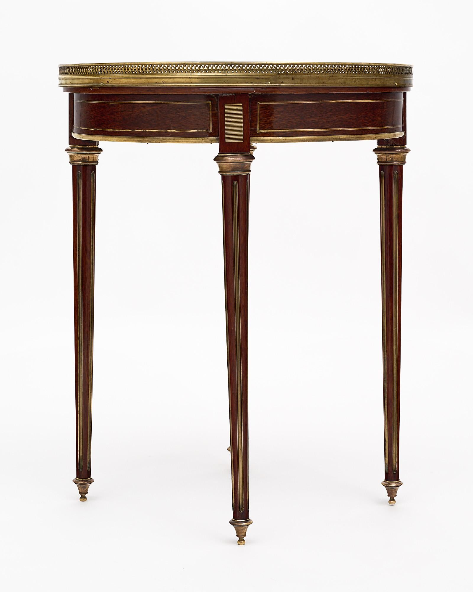 Side “bouillotte table”, French made of mahogany that has been finished in a lustrous French polish. The top is an intact “Breche royal” marble surrounded by brass. This table also features brass “toupie” feet and gilt brass fluting.