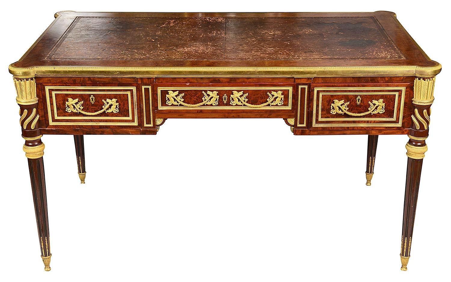 A fine quality late 19th century French Mahogany Bureau plat in the Louis XVI style. Having an inset leather top, writing slides to either side, mercury gilded ormolu mounts and mouldings, three frieze drawers, arrow quiver like ormolu mounts above