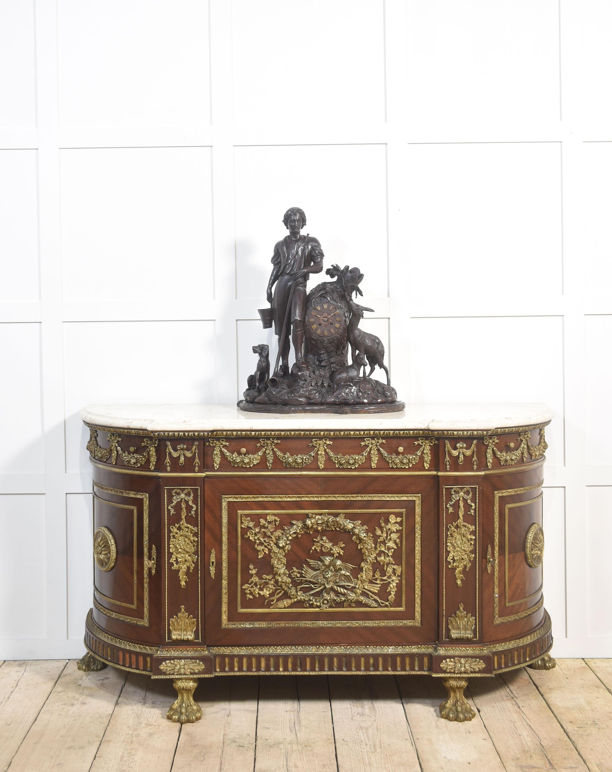 Credenza in mogano in stile Luigi XVI con profonde decorazioni in ormolu e un piano in marmo bianco sagomato e ben figurato. Sopra un unico cassetto a fregio con volute floreali sopra un'anta centrale montata con una corona d'alloro, affiancata da
