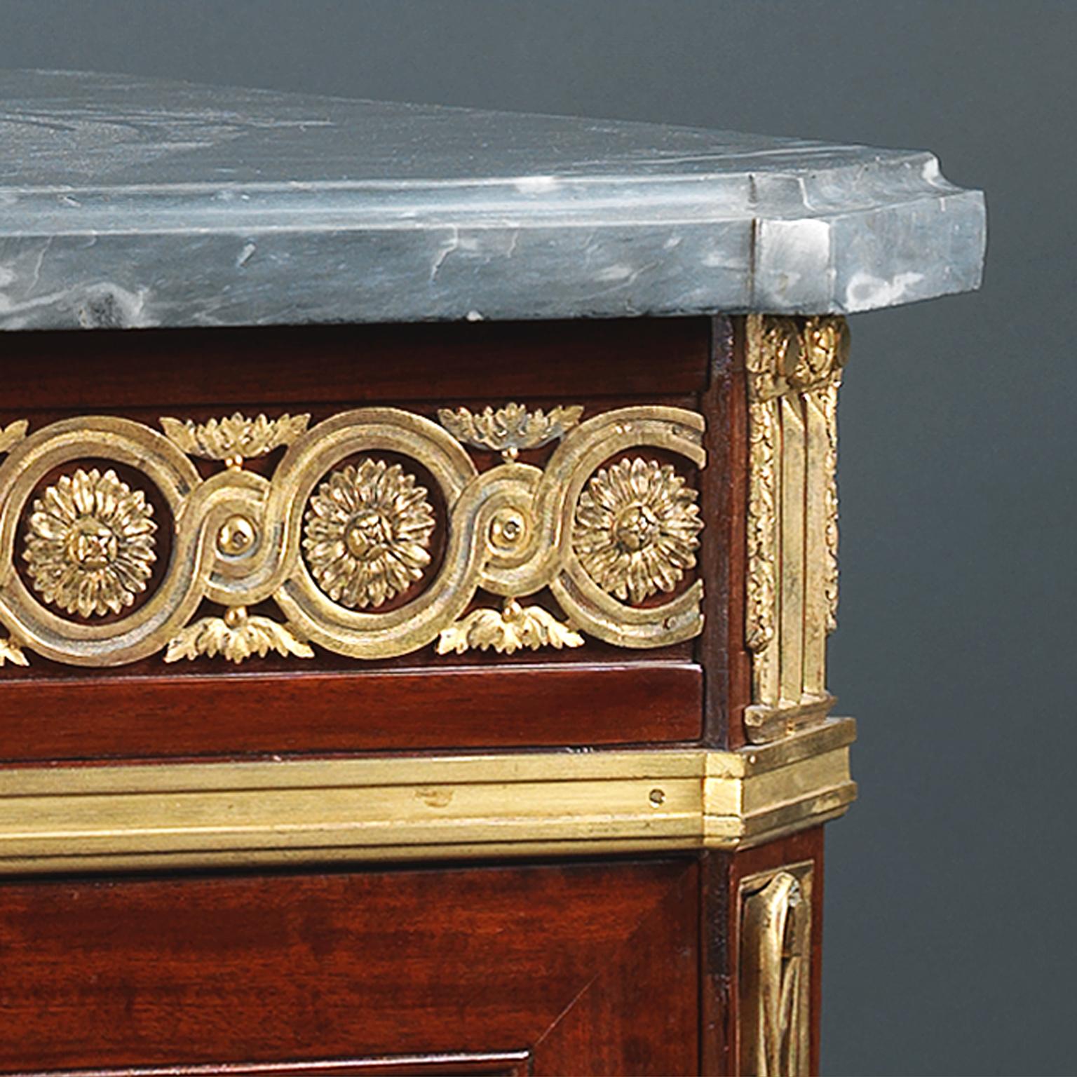 Kleine vergoldete Bronzekommode aus Mahagoni im Louis XVI-Stil mit grauer Marmorplatte. 

Diese schöne Kommode hat eine geformte graue Marmorplatte mit abgeschrägten Ecken, über einem Fries mit Goldbronze-Guilloche und Blumenkopfbordüre.  Darunter