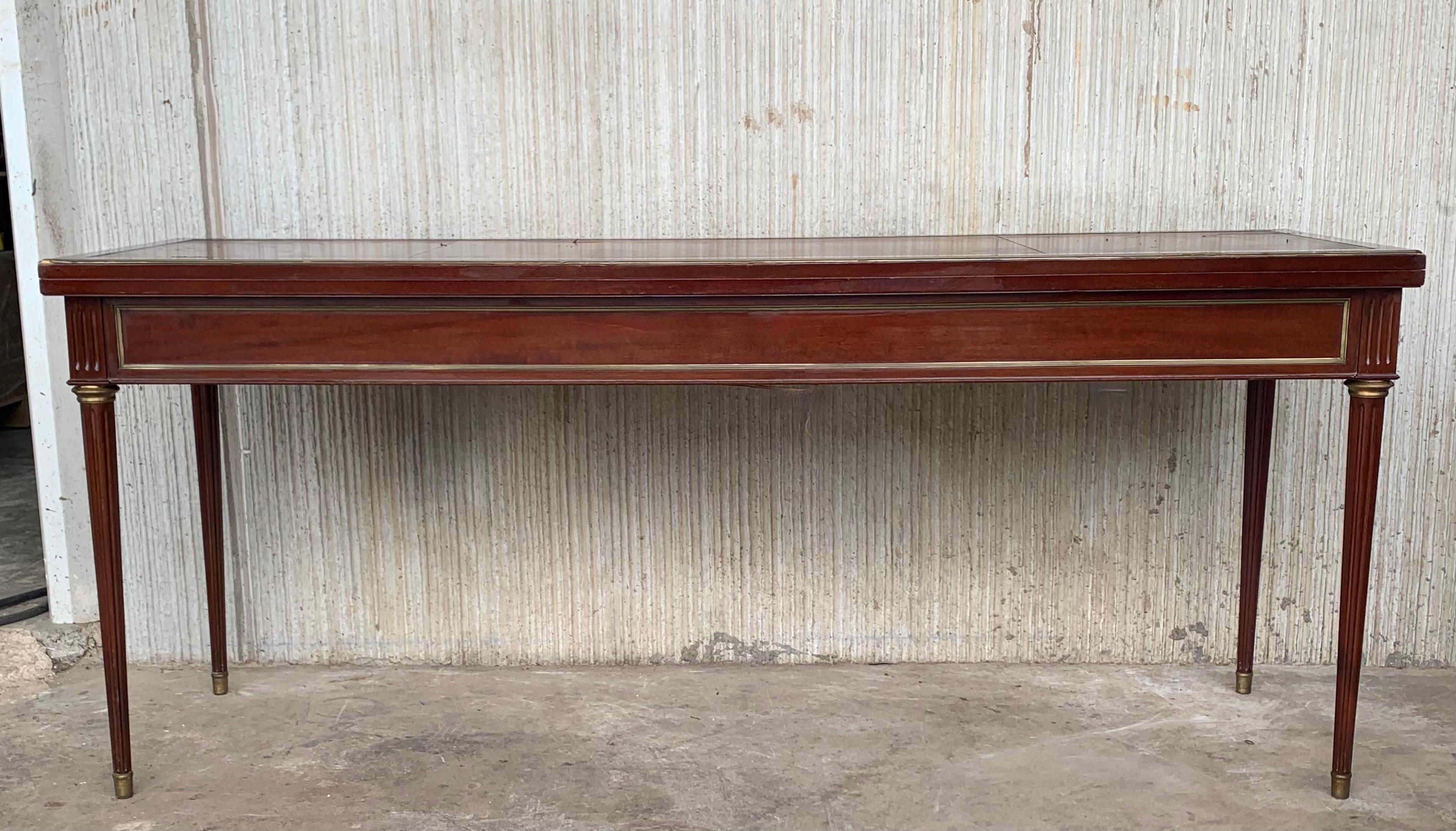 Louis XVI style (19th century) mahogany large console table with a fold-open top, brass trim detail, and tapered fluted legs ending in brass end caps.
The console top has a leather top that it needs to be reupholstered. We will ship the piece with