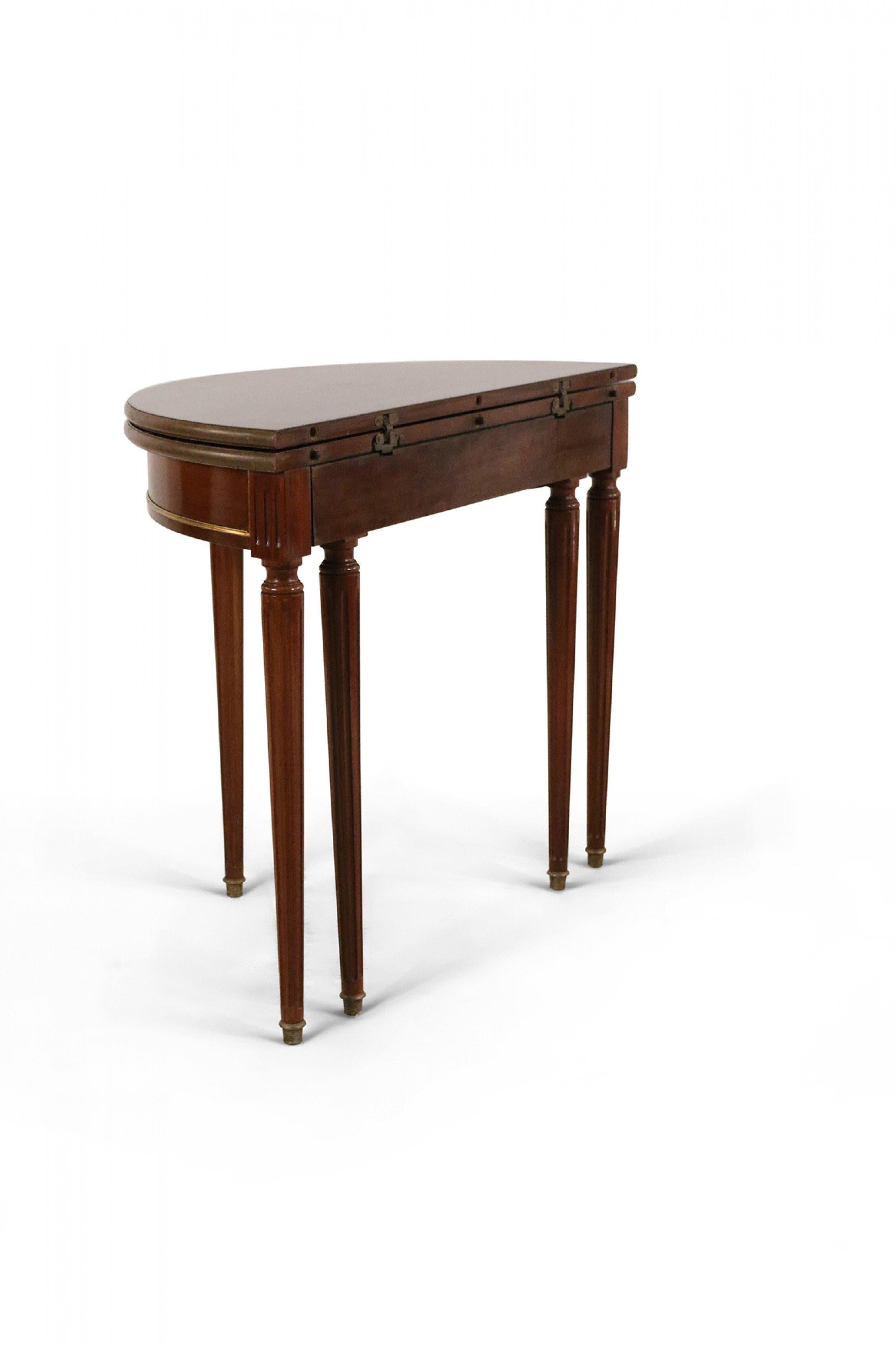 Louis XVI style (19th century) mahogany demilune console table with a fold-open circular top, brass trim detail, and five tapered fluted legs ending in brass end caps.