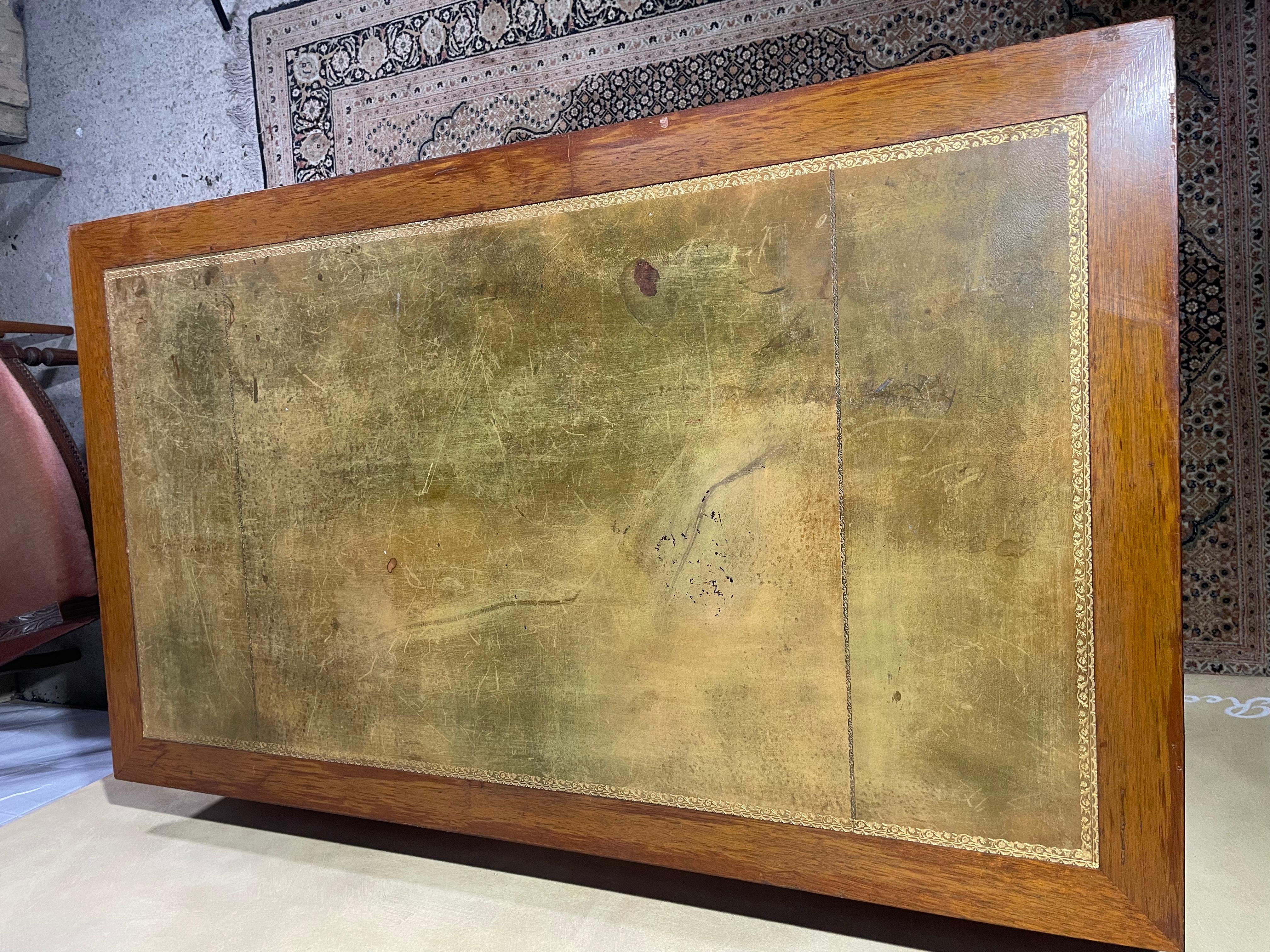 This elegant early 20th-century Louis XVI-style desk is crafted from rich mahogany and features a gold-tooled leather writing surface, exhibiting minor scratches consistent with age and use. It offers five functional drawers on one side, while the