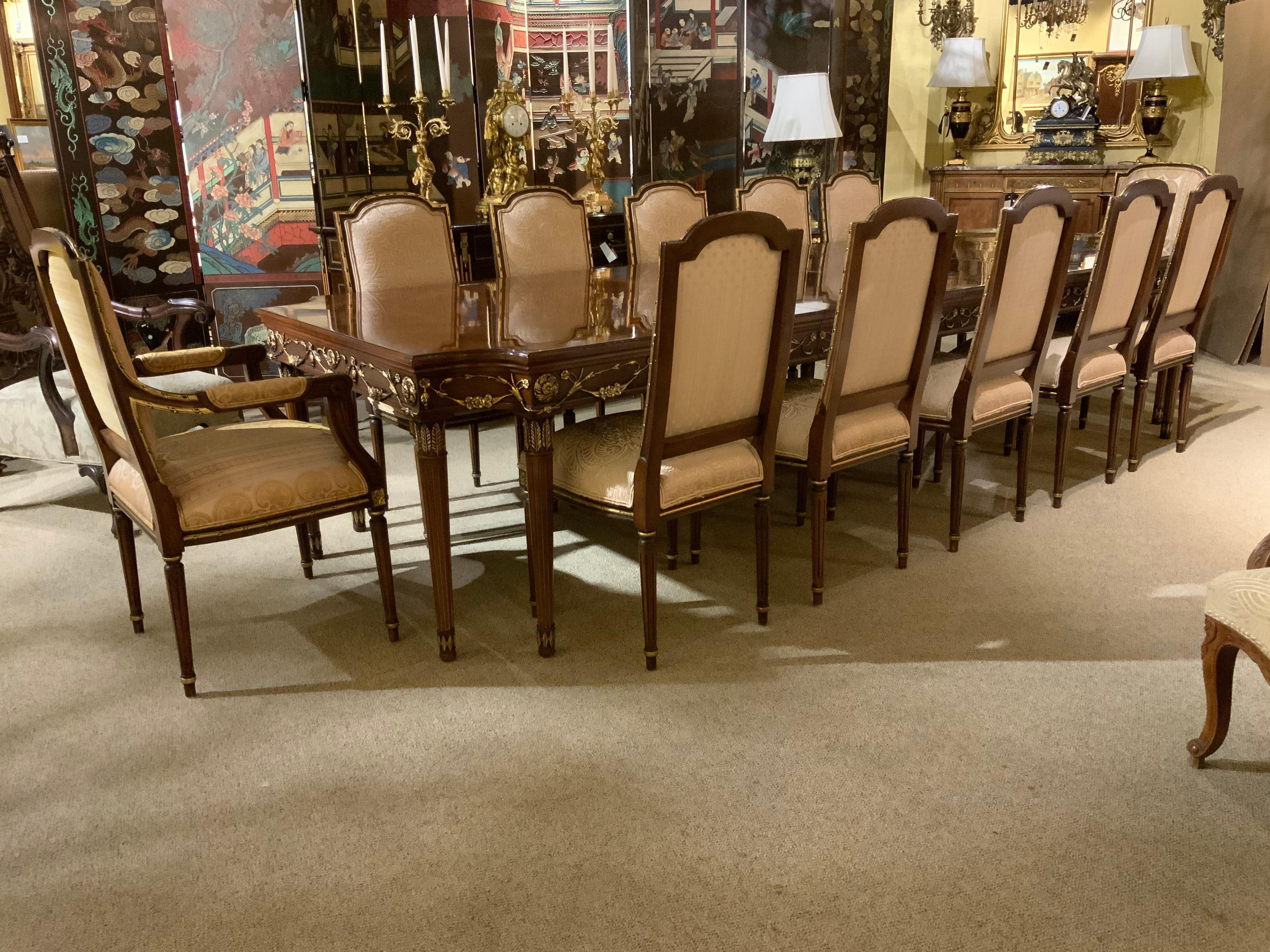 Exceptional dining suite consisting of a large table with inlay of patterned veneers and ebony
Border. The apron is beautifully embellished with raised gilt carvings in a foliate and leaf design 
Set consists of 10 side chairs and a host and