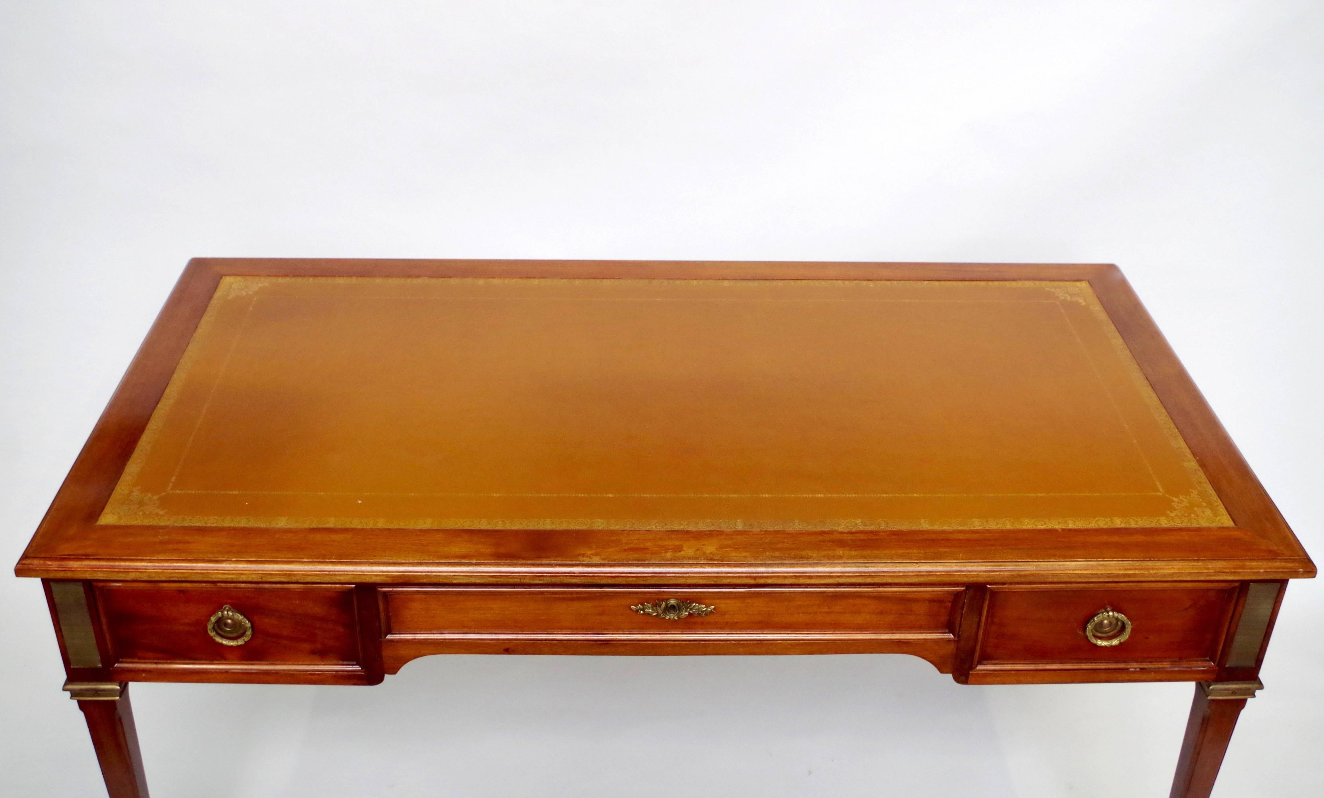 Louis XVI style flat desk, in mahogany with two writing slides.
Standing on four sheathed legs with square shoes and showing tree drawers on the apron. Tawny leather on the top hit with little golden irons and also on the two retractable writing