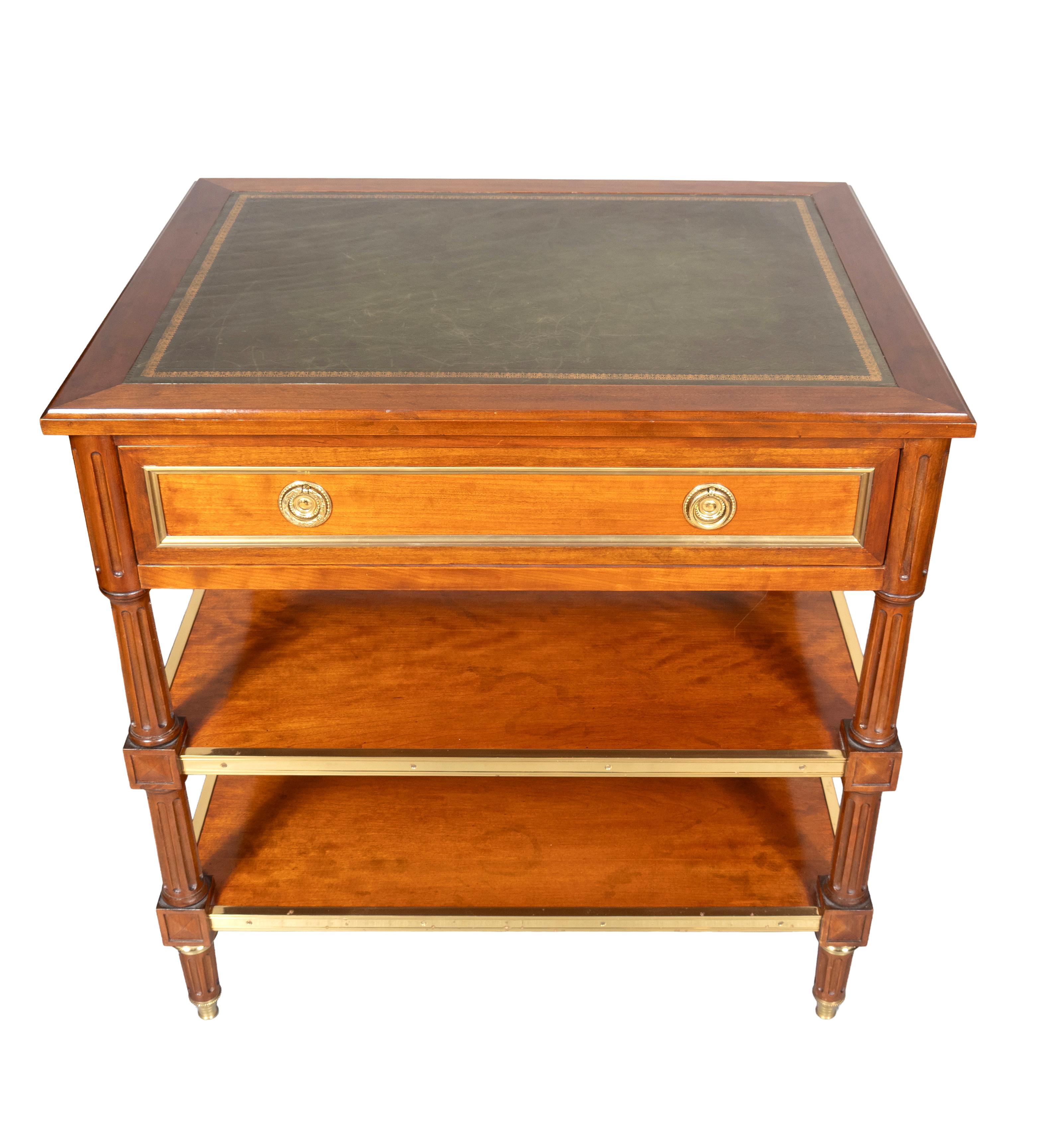 Rectangular top with inset green leather with wood surround. Frieze drawer with brass borders. Finished all around. Fluted legs joined by two conforming shelves. Circular fluted tapered feet. Brass sabots. Frederick P. Victoria reproduction.