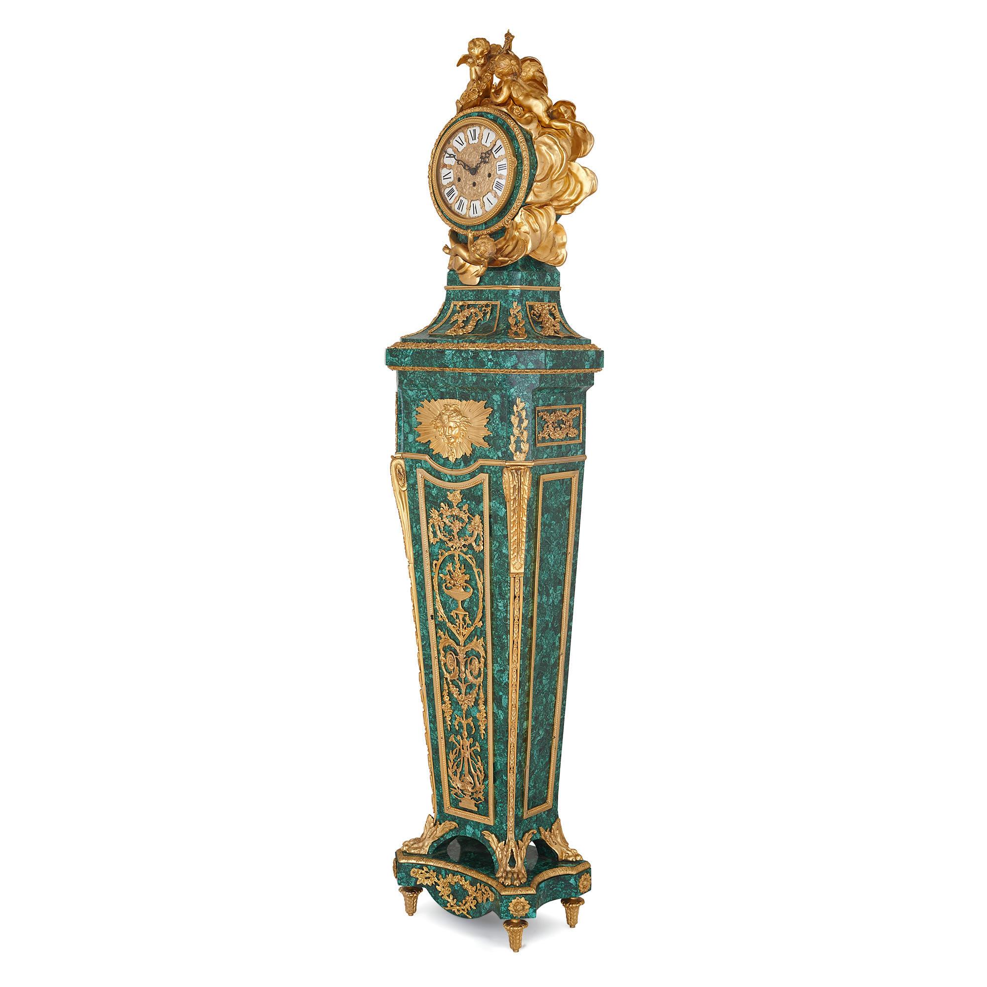 This elegant longcase clock was crafted in the early 20th century, with later malachite veneer, after a design by Jean-Henri Riesener, the acclaimed French 18th century cabinetmaker. The piece is crafted in the Neoclassical ‘Louis XVI’ style, which