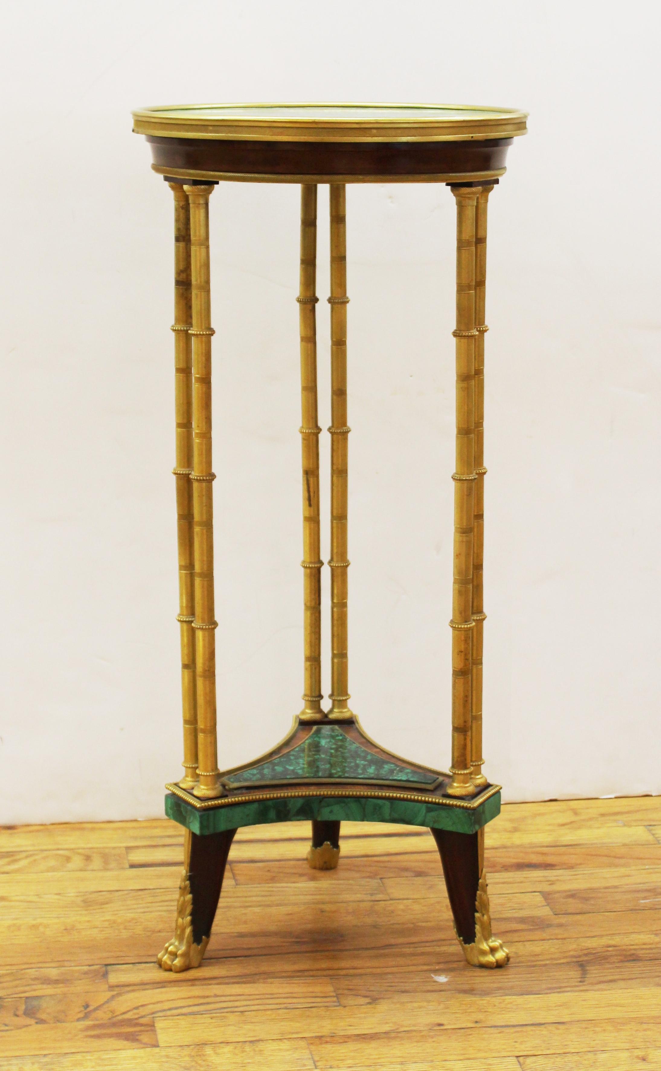 French Louis XVI style malachite gueridon table with ormolu mounts, the circular top tier supported on cluster legs of bamboo shape, the columns joined by a concave-shaped lower tier with malachite elements, in typical style of Adam Weisweiler,