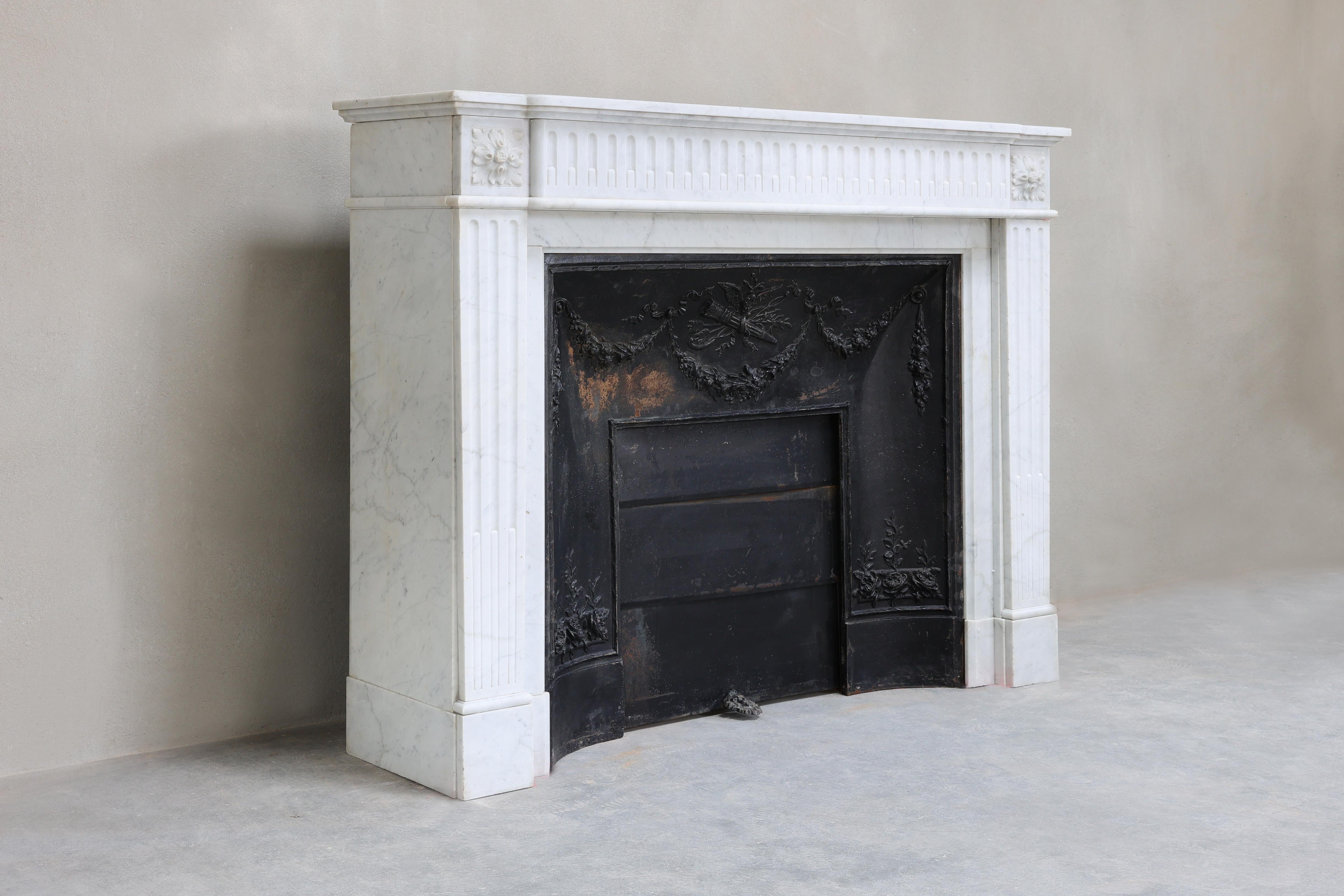 Beautiful Carrara marble fireplace with cast iron insert. This fireplace dates from the 19th century and is in the style of Louis XVI. A beautiful fireplace with fluting on the legs and in the top! This white marble gives calmness and a chic look.