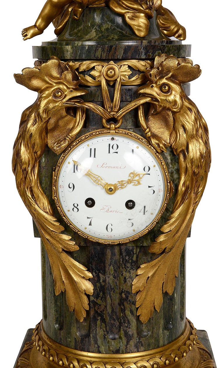 A fine quality late 19th century green figured marble column mantel clock, mounted with cherub in the clouds holding a garland of flowers above a pair of gilded ormolu birds supporting the white enamel clock face, an eight day duration movement,