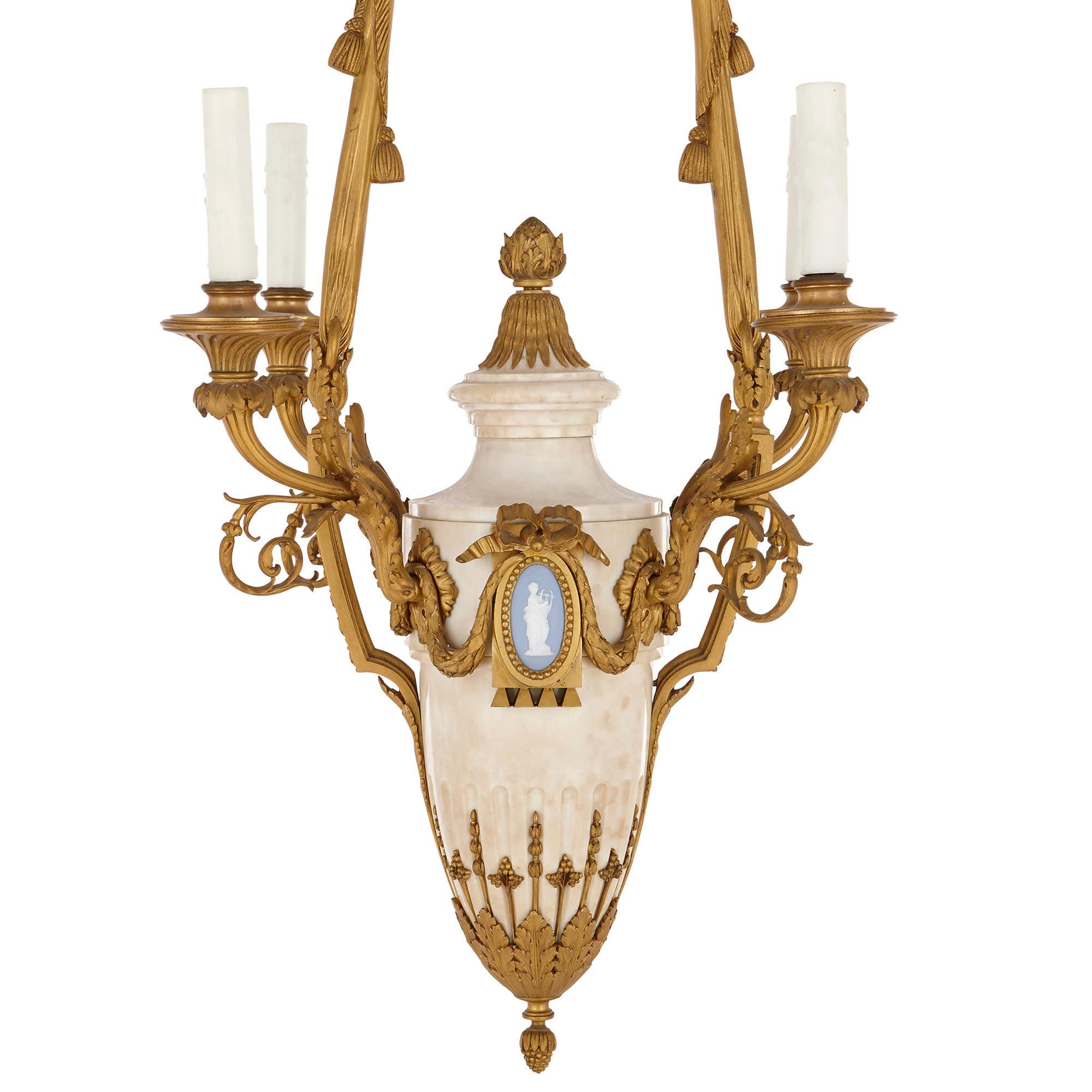 This four-light chandelier is designed in the so-called ‘Louis XVI style’—a refined Neoclassical style, which came into fashion in France during the reign of King Louis XVI (1774-1793). 

The chandelier is comprised of a white marble body which is