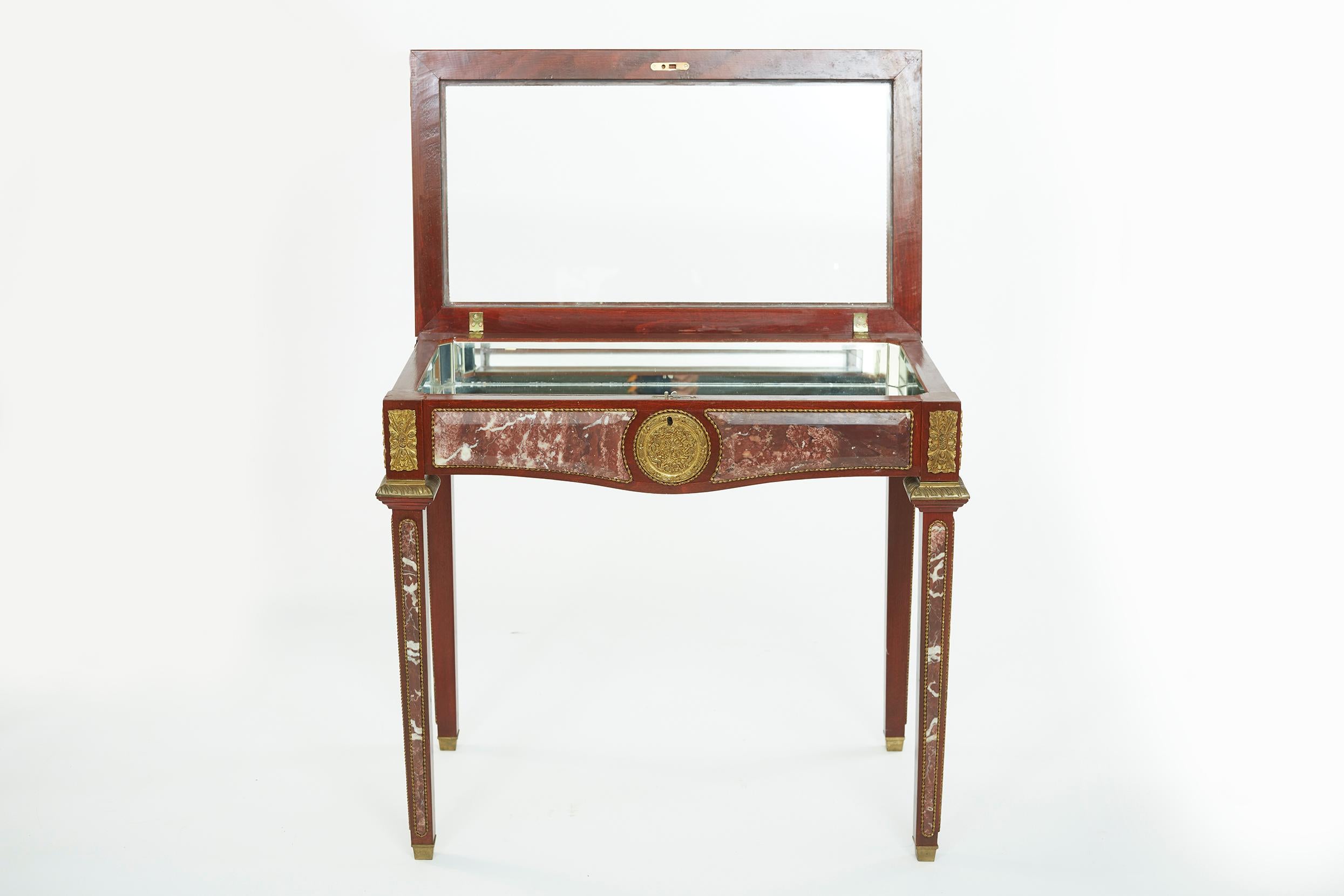 Louis XVI style marble and ormolu bronze mounted mahogany vitrine display table with mirrored interior , supported by four tapering legs . The vitrine is in great condition . Minor wear consistent with age / use . Small hairline in one side of the