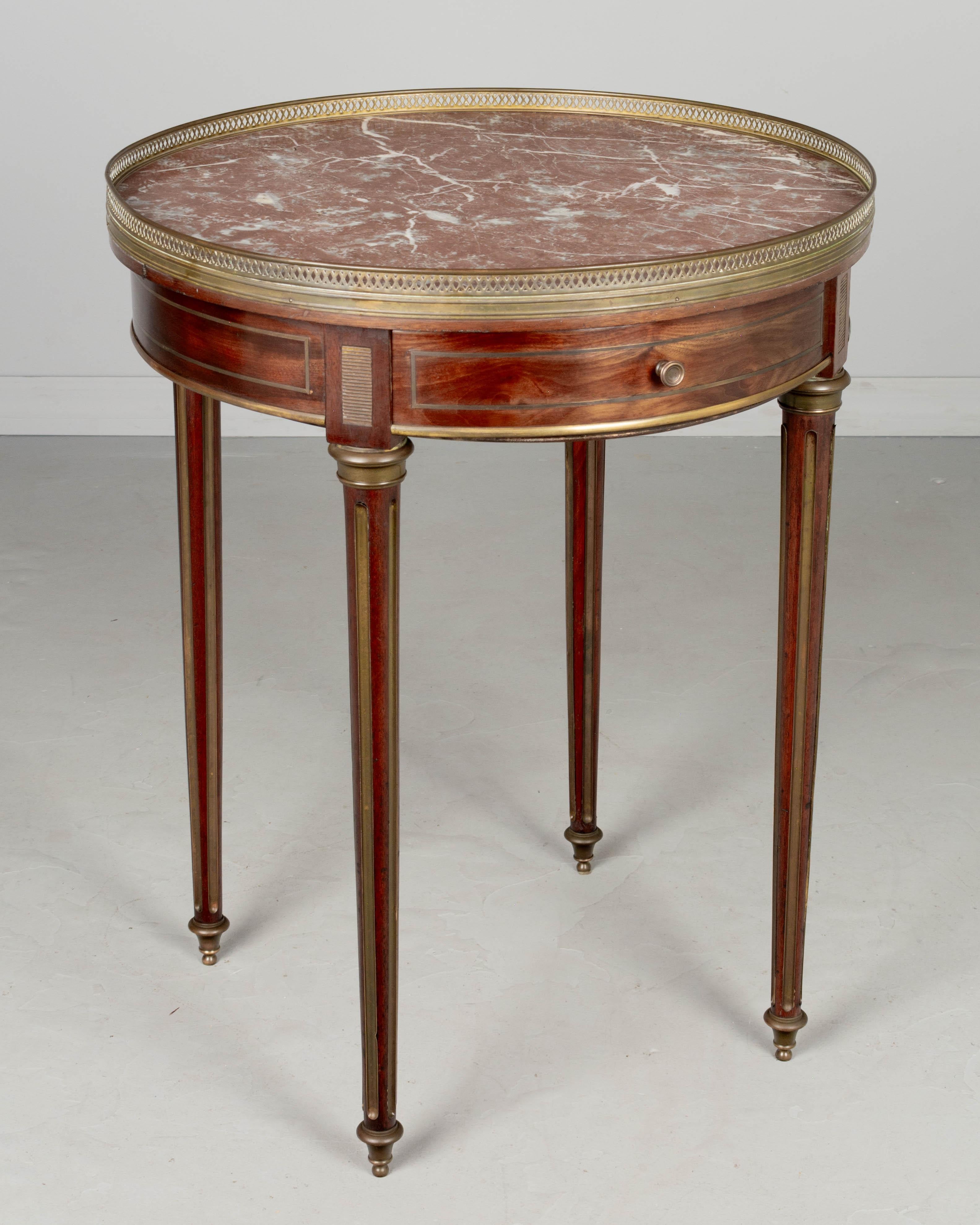 A Louis XVI style mahogany bouillotte table with a small drawer, fluted tapered legs and original Laguedoc red marble top. Inlaid brass details, sabots and gallery. Circa 1900-1920.
30