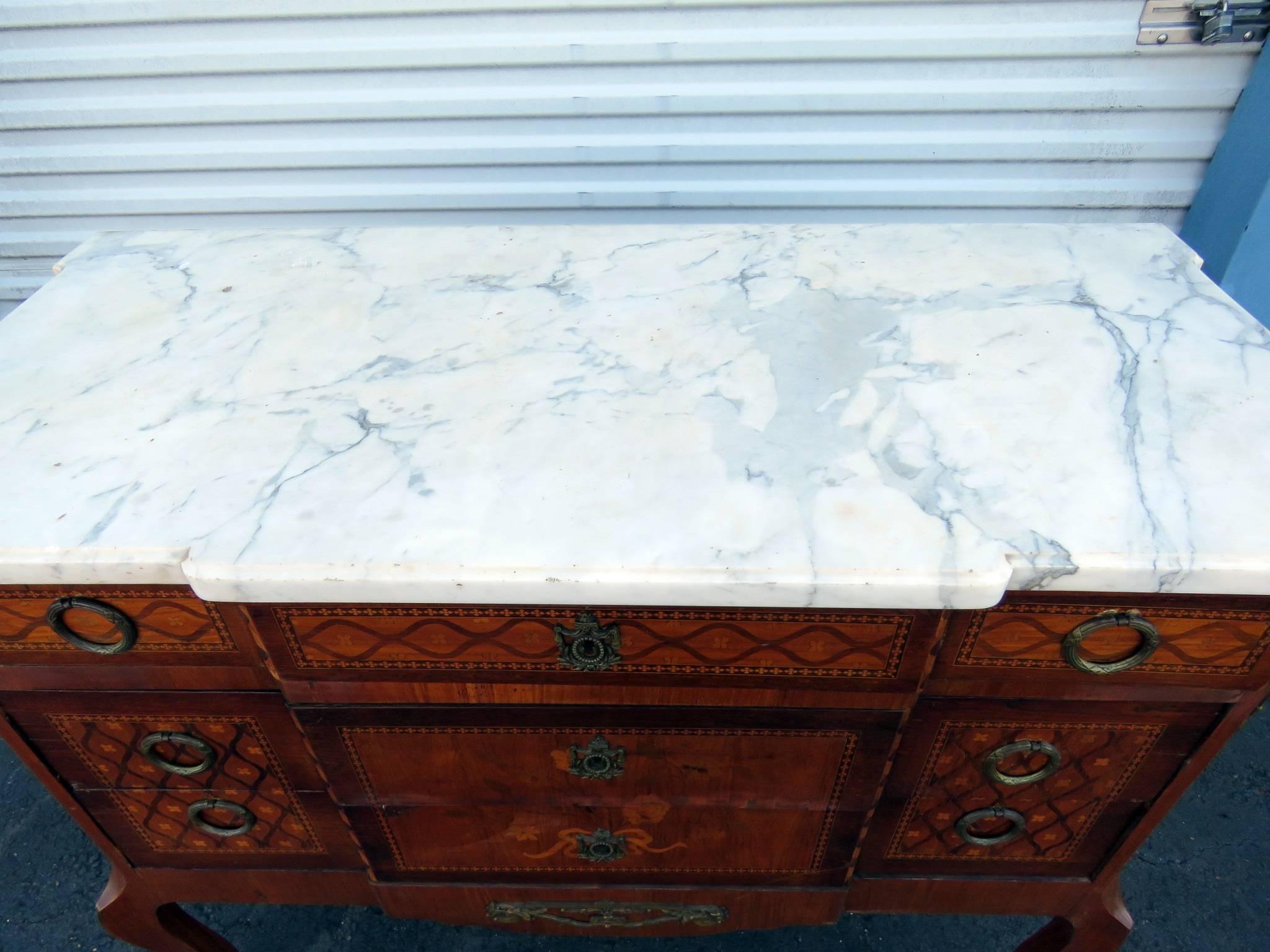 Louis XVI style parquetry inlaid marble-top commode with bronze mounts and three drawers.