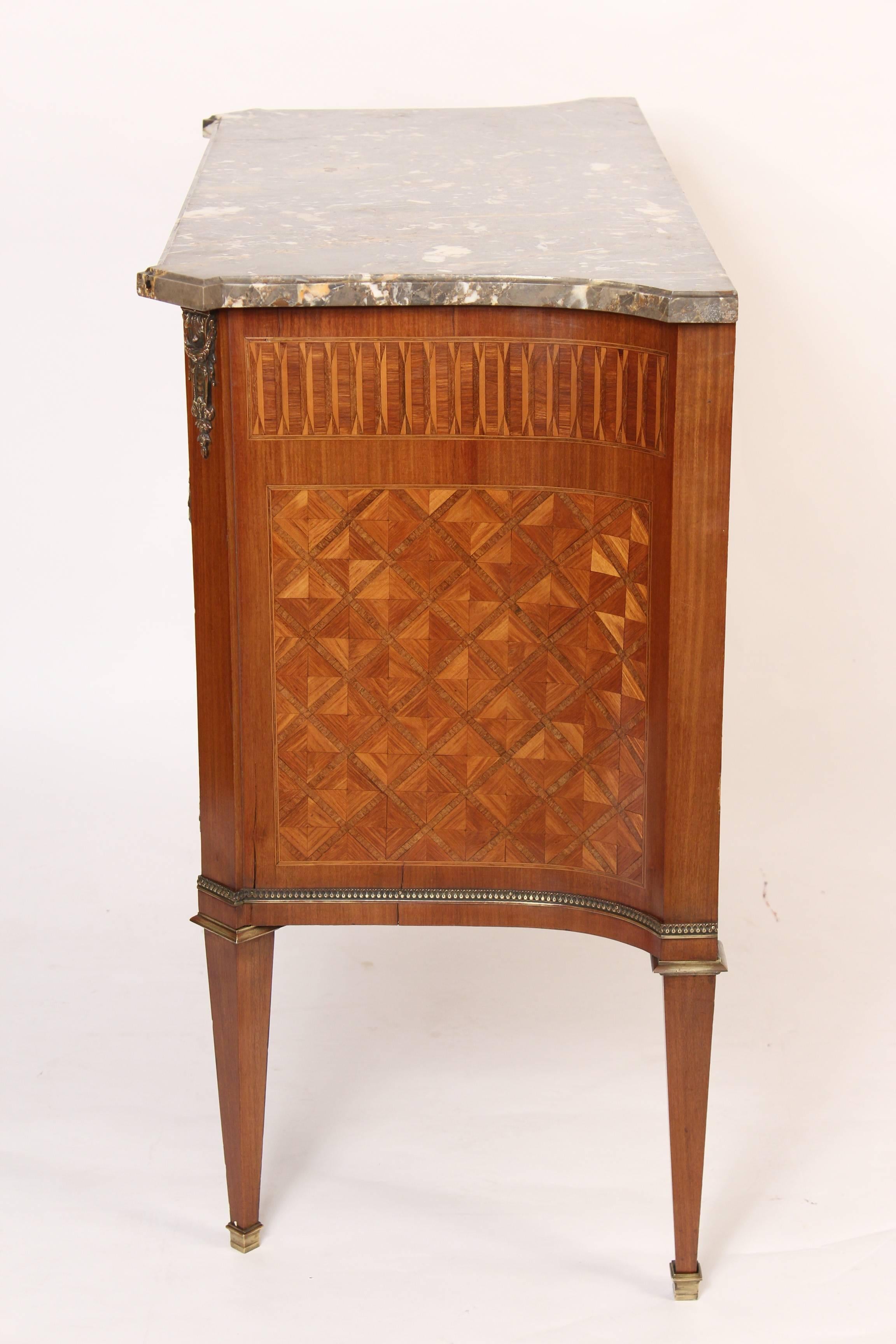 Louis XVI style tulip wood, satinwood, and mahogany parquetry inlaid bronze-mounted commode with a marble top, circa 1920s. Stenciled under marble France.
