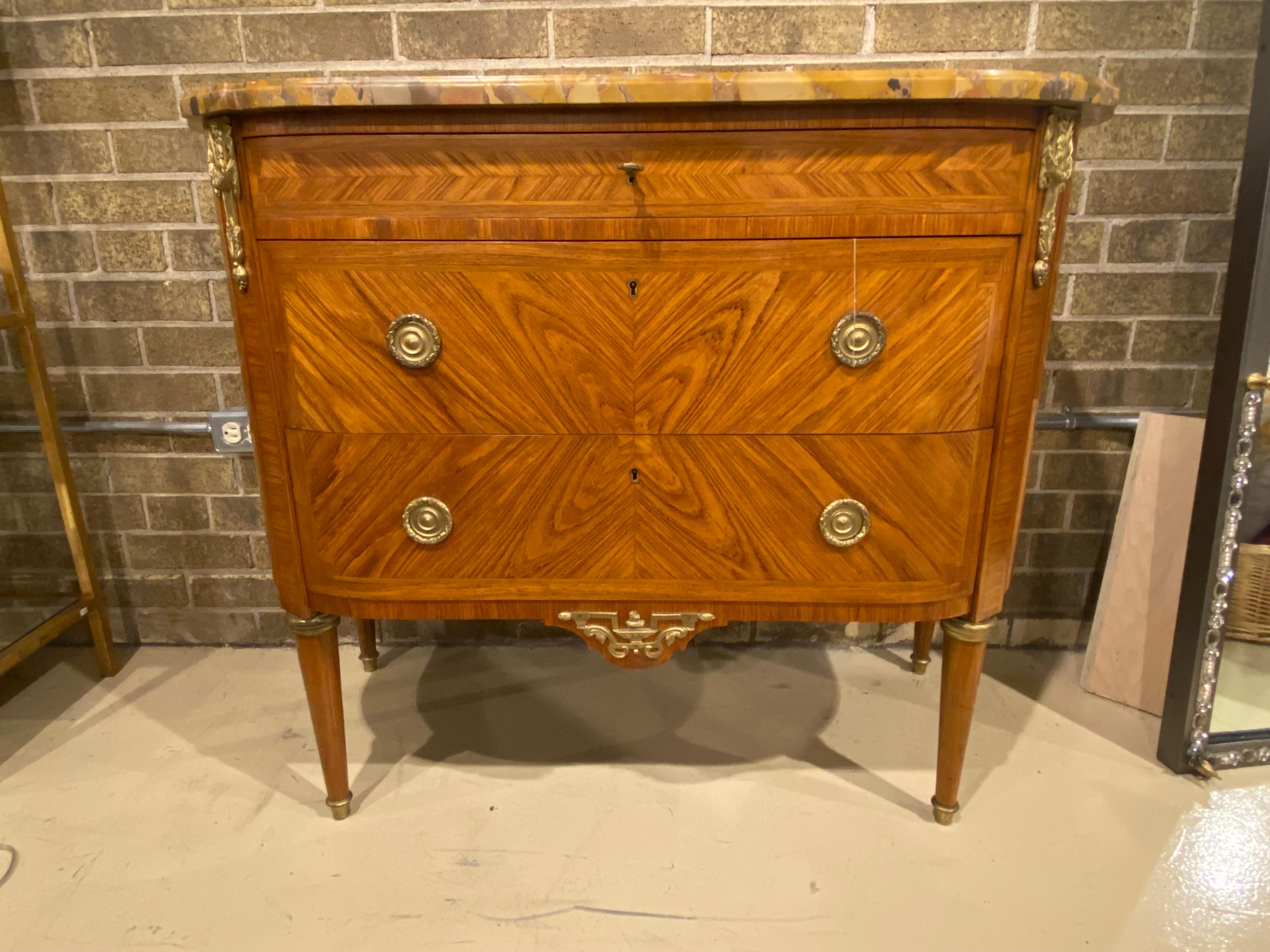 A beautifully proportioned French Louis XVI Style Marble top Demi Lune shape Commode with Ormolu Accents and three curved front drawers. The Kingwood parquetry is subtle but elegant and accented with modest but present brass or ormolu mounted