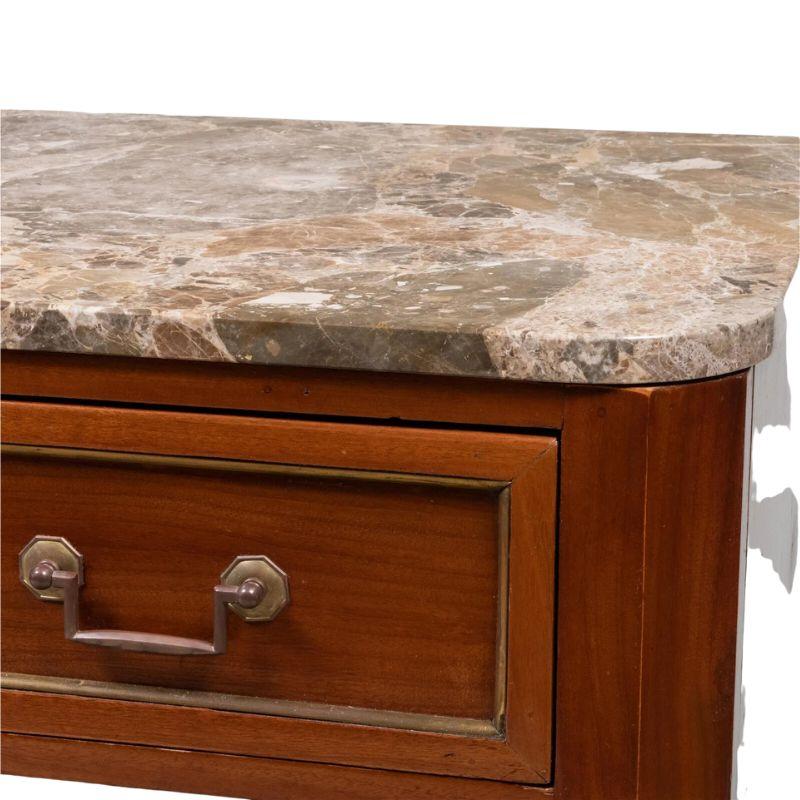 A Louis XVI style marble top mahogany commode with brass detail and hardware mounts.  The chest has three drawers, each with an inset panel in front highlighted with brass trim, brass rectangular drawer pulls and center brass detailed key holes. 
