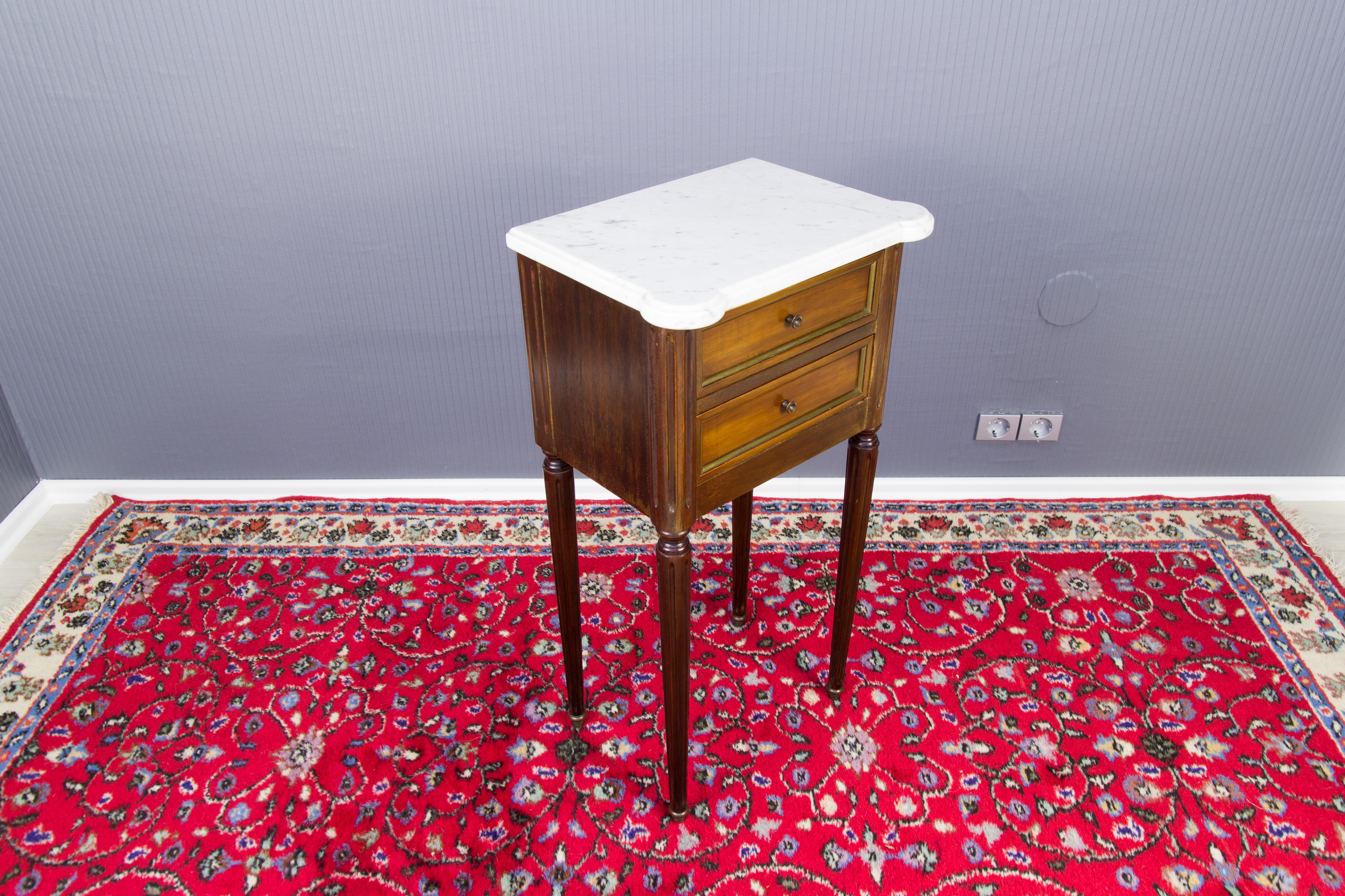 French Louis XVI style walnut side table, nice shaped white marble top. Antique bedside table or cupboard has two lined frieze drawers with brass button pulls. The side table is raised on four elegant turned and fluted supports terminating in brass