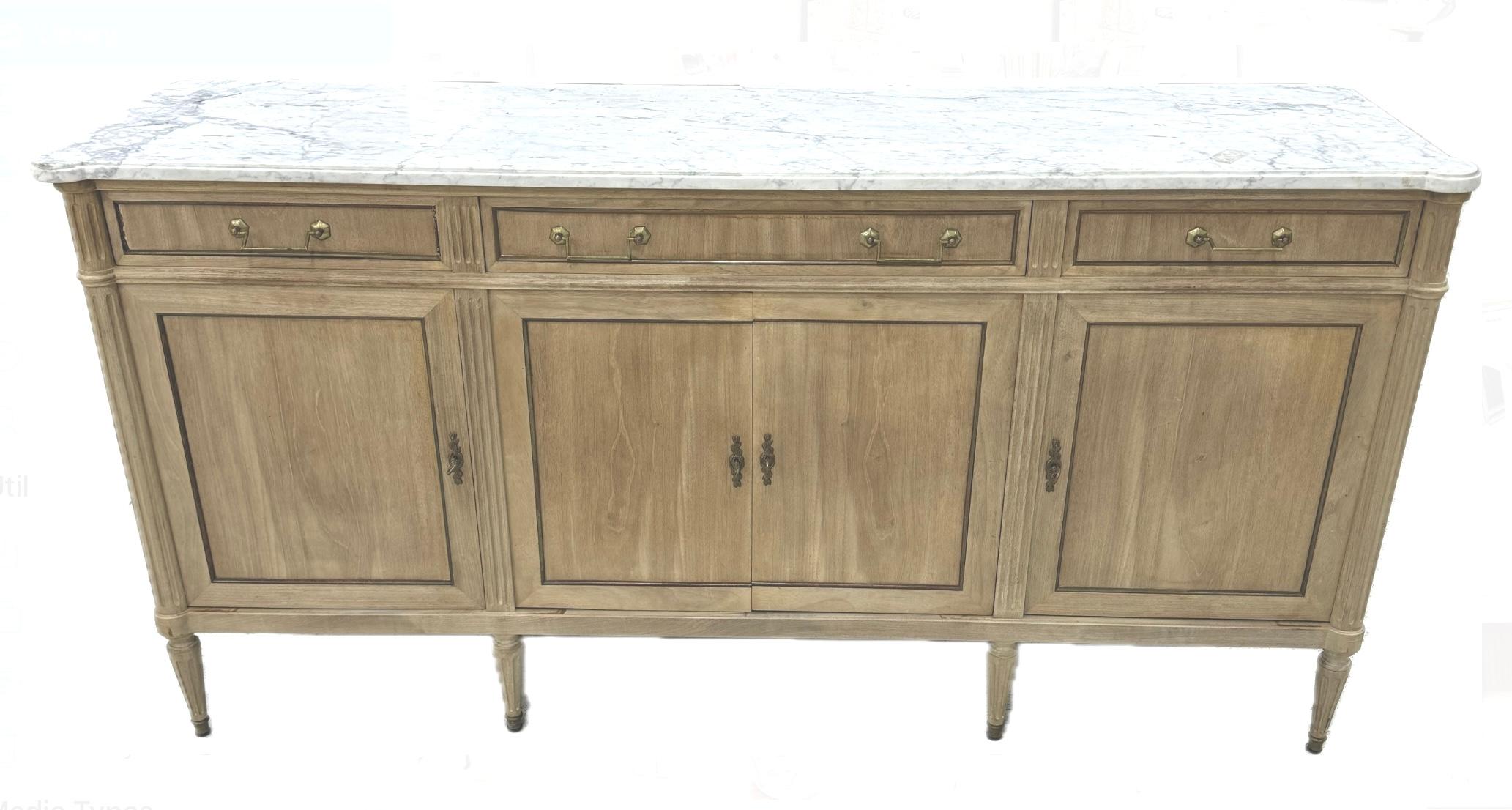 Fabolous French Louis XVI style enfilade or sideboard. Features a marble top above three upper drawers, over four doors leading to interior storage. Sideboard also features bronze hardware and rises on fluted tapered legs. Wonderful bleached