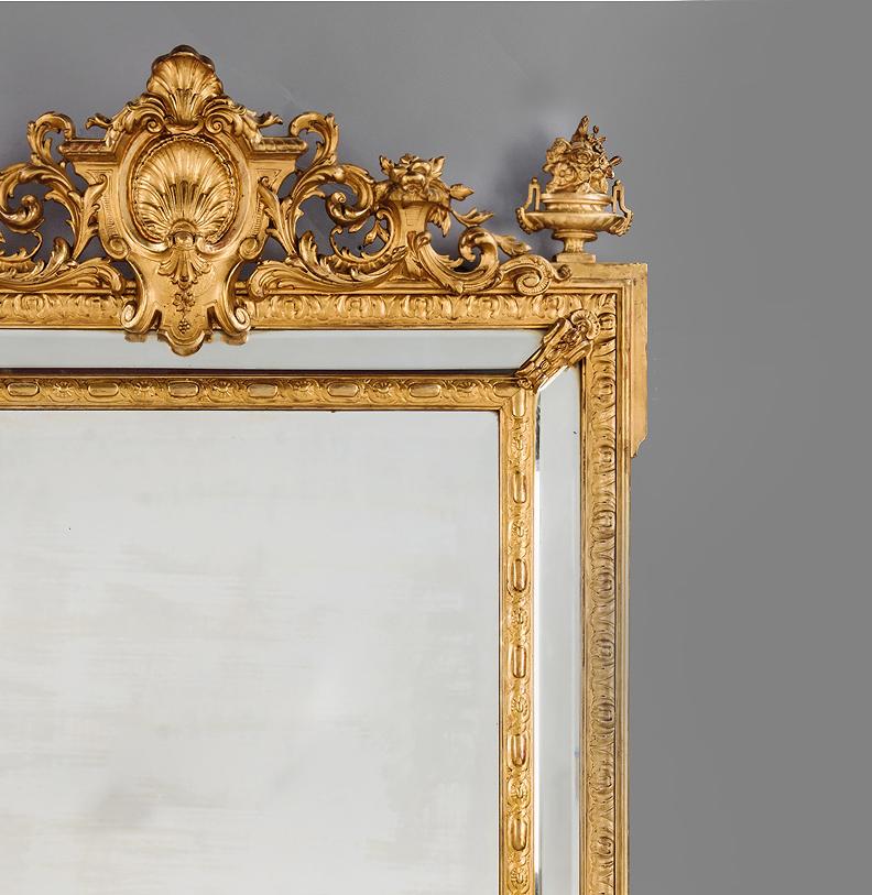 A fine Louis XVI style marginal frame mirror.

This finely caved giltwood and gesso mirror has a rectangular mirror plate framed by marginal borders of bevelled glass and surmounted by a scrolled foliate cresting centred by a scallop shell