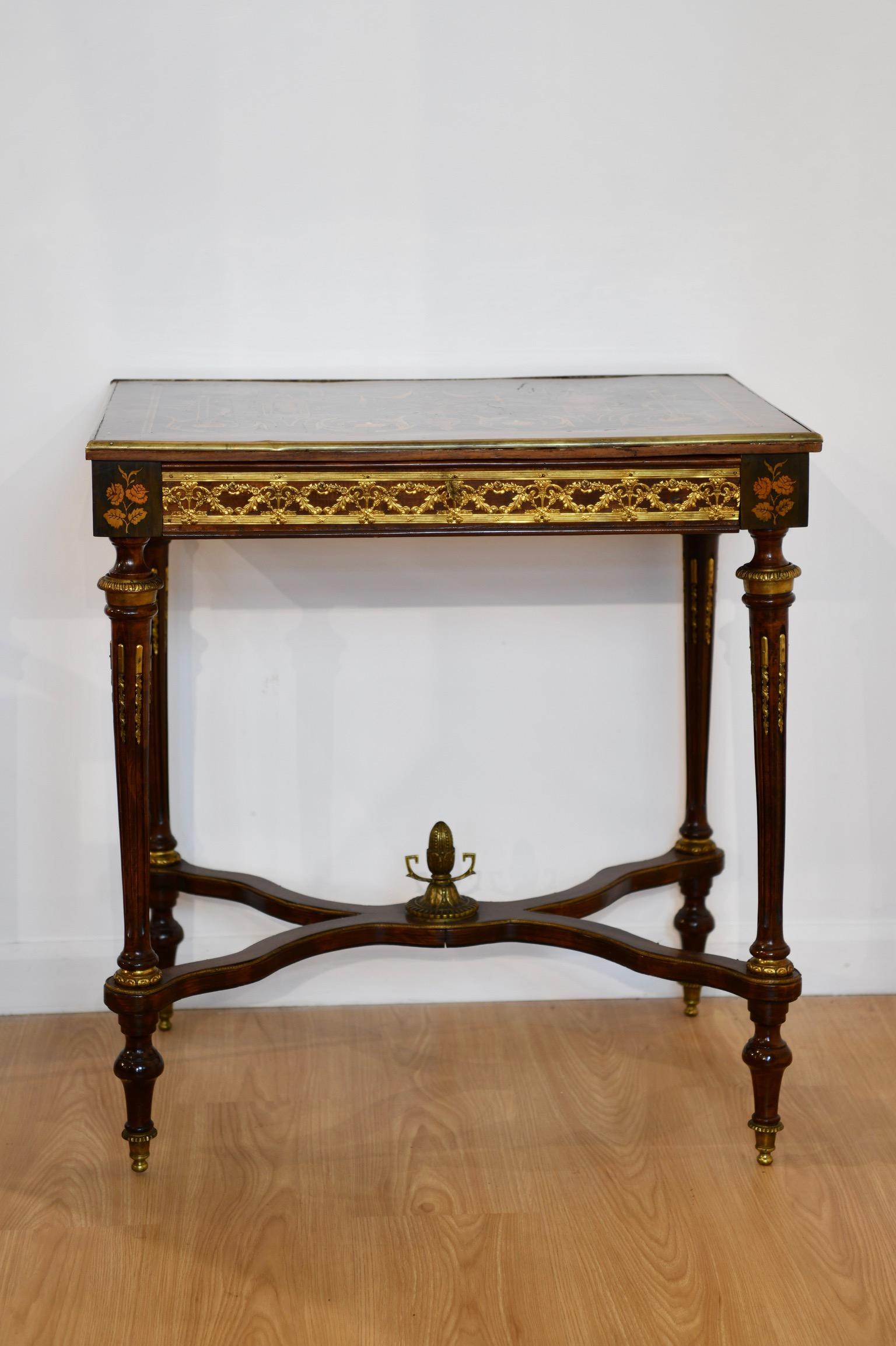 Louis XVI-style marquetry inlaid writing table with Neoclassical motif and mother of pearl inlay over gilt bronze mounted apron with single drawer. Table raised on tapered reeded legs with acorn finial mounted stretcher. Dimensions: 29