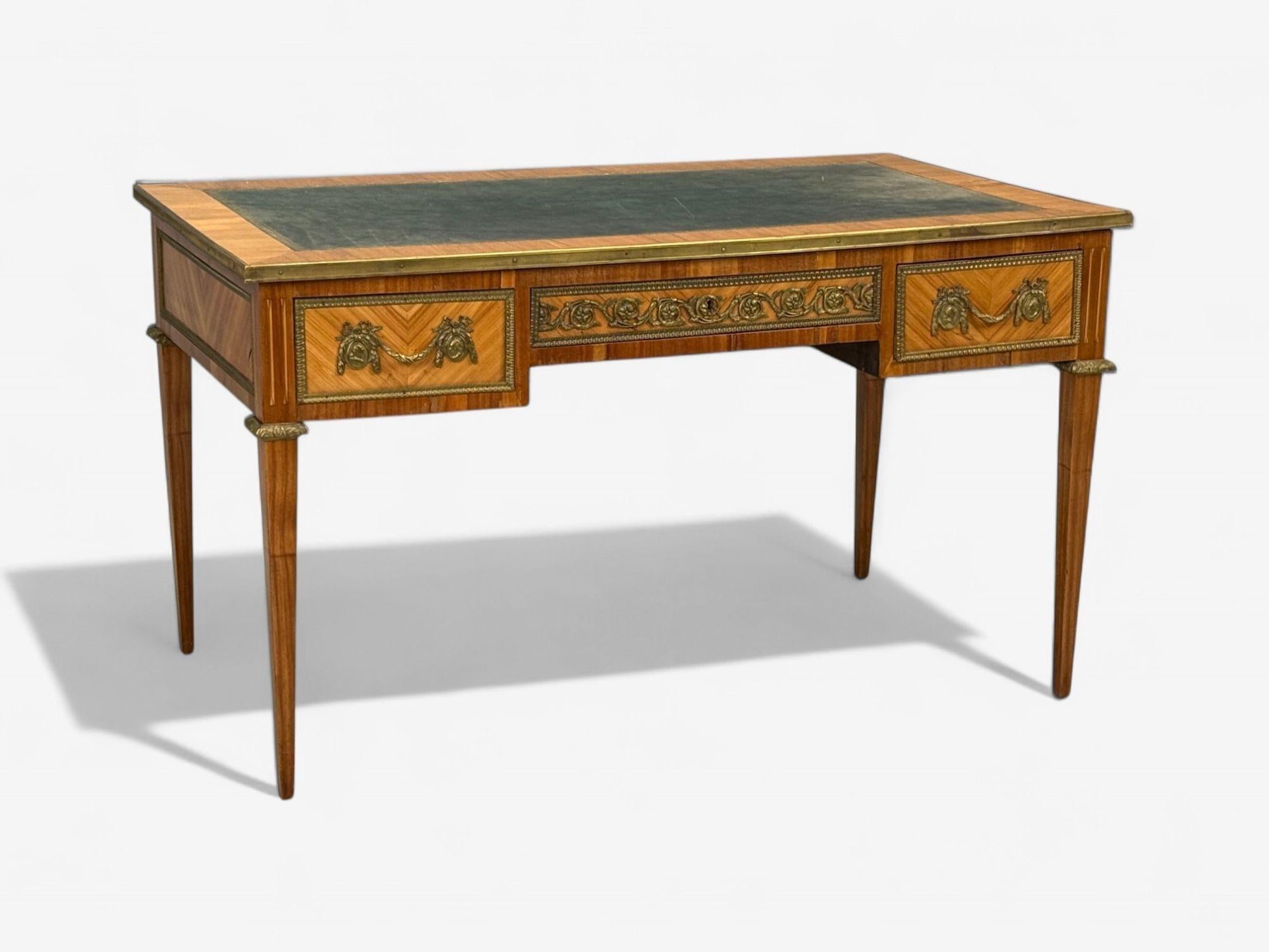 Scrivania in stile Luigi XVI, intarsio, pelle, Francia, XIX secolo.

Uno scrittoio con piano in intarsio, bronzo patinato e pelle lavorata, prodotto nella Francia del XIX secolo, con tre cassetti estraibili e uno schienale rifinito in modo