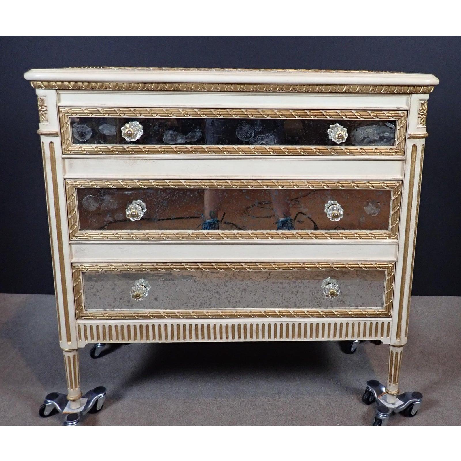 Louis XVI style mirrored chest of drawers. Carved, painted and gilt three-drawer chest has mirrored panels top, sides and each drawer.
  