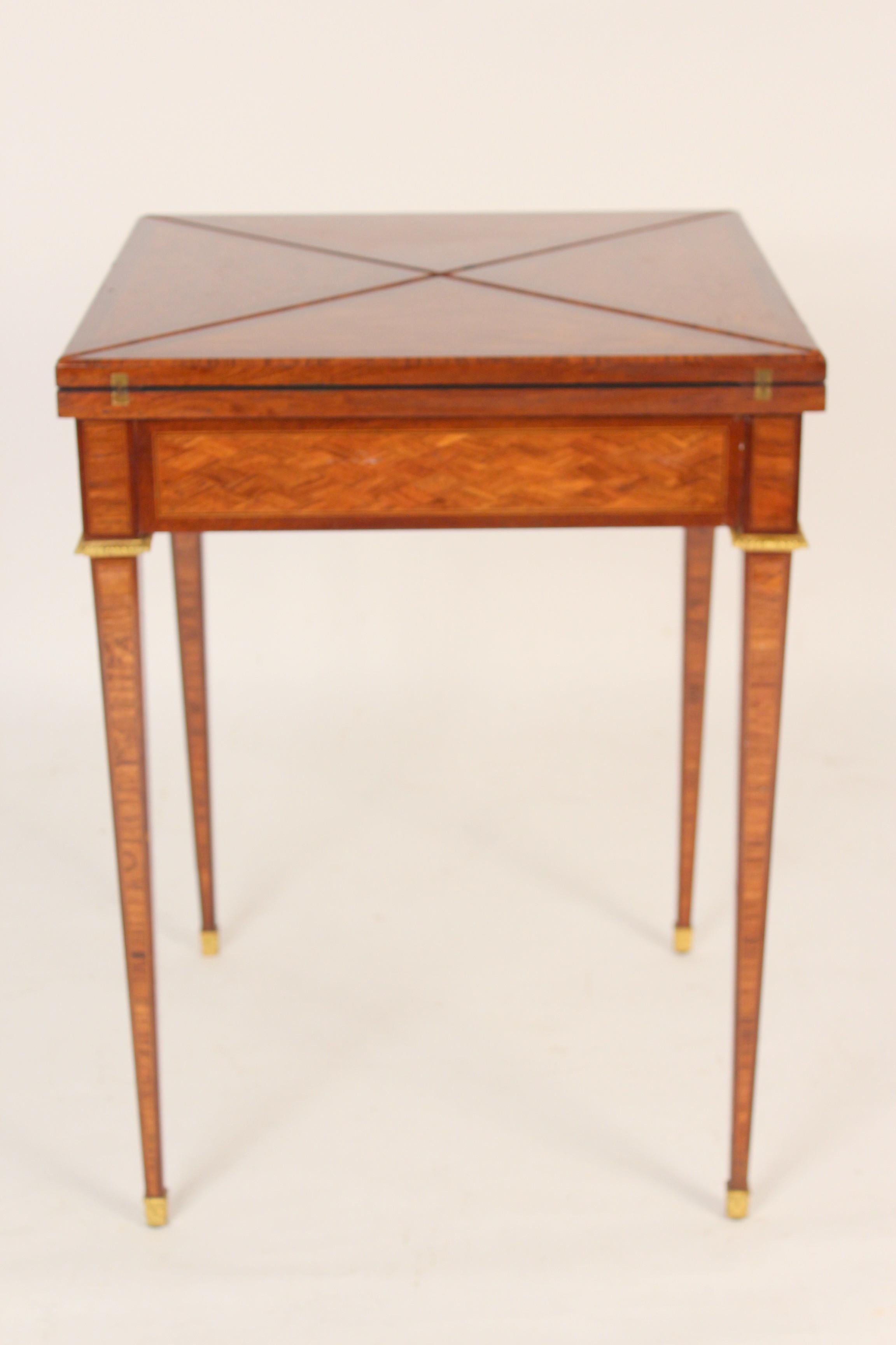 Louis XVI style tulip wood and mahogany napkin fold games table with gilt bronze mounts and a tooled leather playing surface., signed (stamped) Haentges, Paris, circa 1920. Dimensions when napkin folds are closed, height 30.5