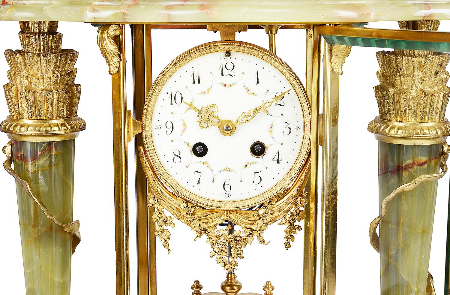 A good quality late 19th century French, onyx and gilded ormolu clock garniture. Having a pair of four branch candelabra on either side, each with arrow sheaths, the clock having an urn finial, a white enamel clock face, an eight day chiming