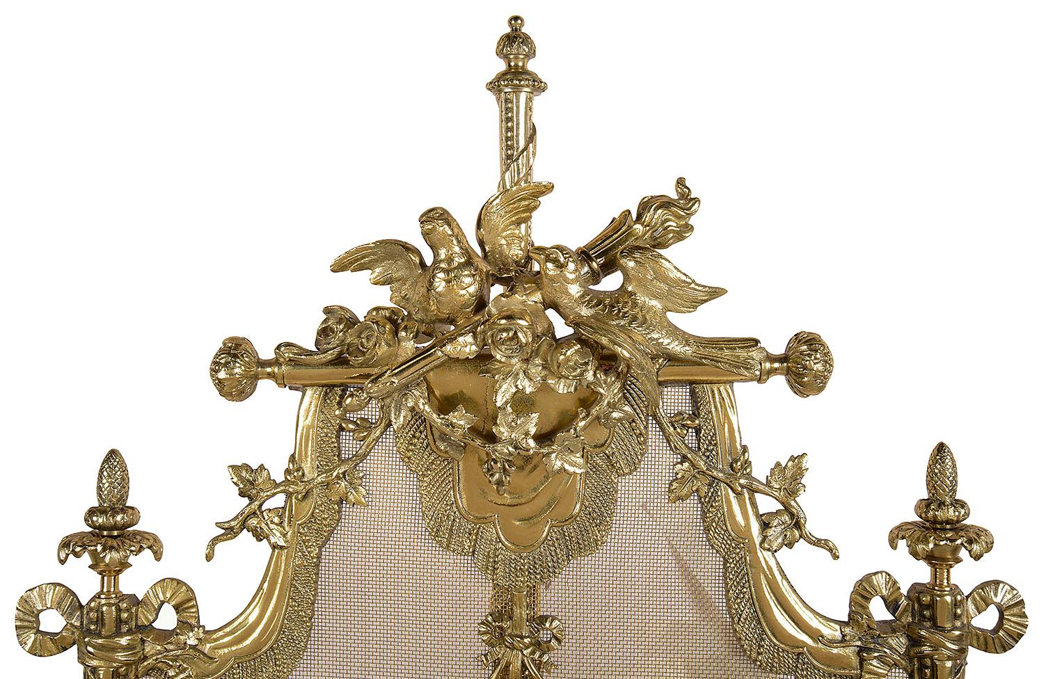 A very good quality late 19th century French, Louis XVI style gilded ormolu fire screen, having a pair of doves either side of a flaming torch, scrolling vine leaves, ribbons and a urn with rams heads, raised on four out splayed legs.
