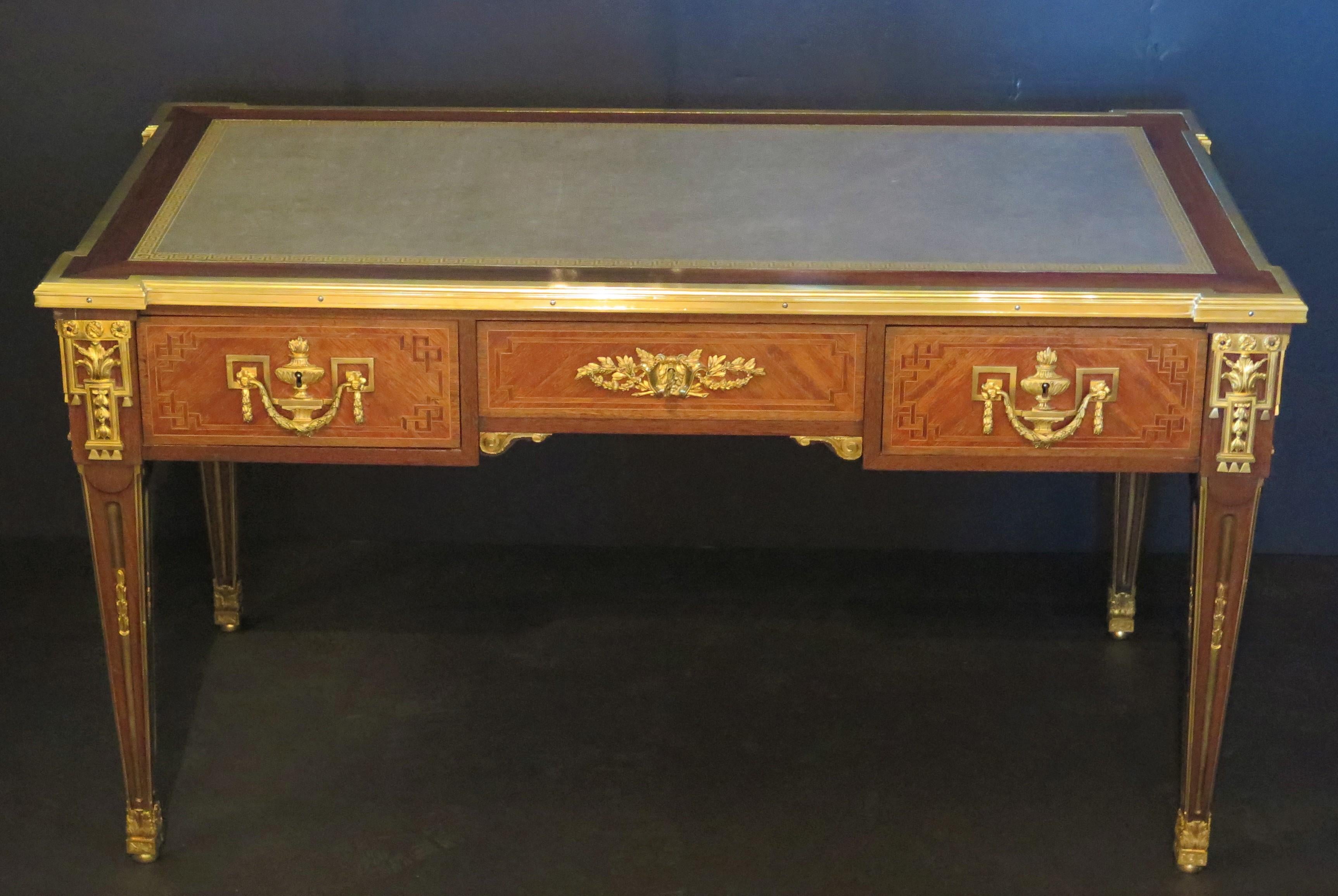 a Louis XVI-style ormolu mounted mahogany bureau plat / desk with rectangular blue-grey leather inset top (new / recently installed) and brass mounted molded edge above three drawers and raised on square tapering legs, with overall decorative ormolu