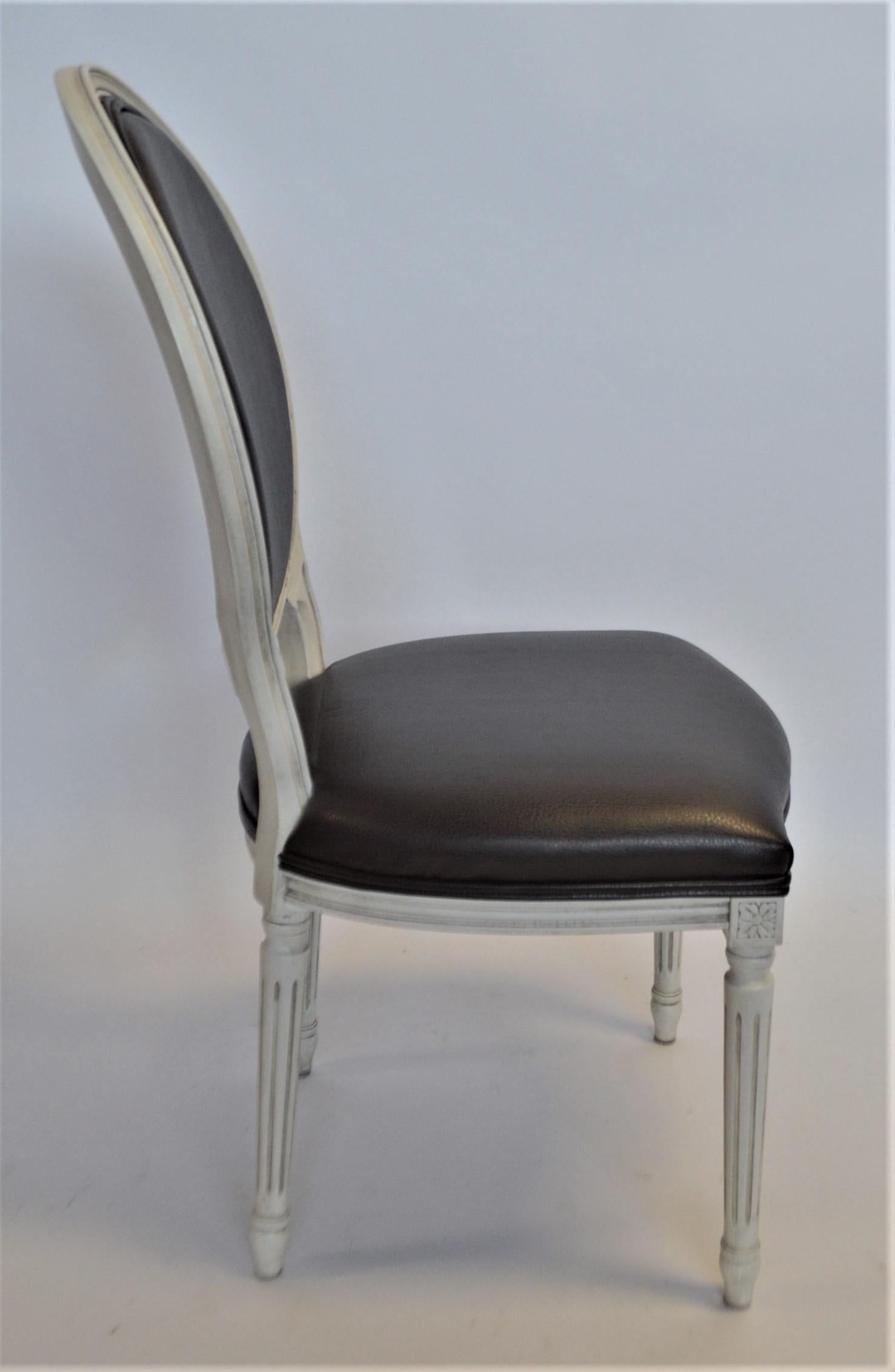 This Louis XVI style oval back dining chair is showing here in a white patinated frame and upholstered in a black faux leather. The frame is made in Italy of solid beech wood. The price includes a custom paint finish or wood stain and upholstery