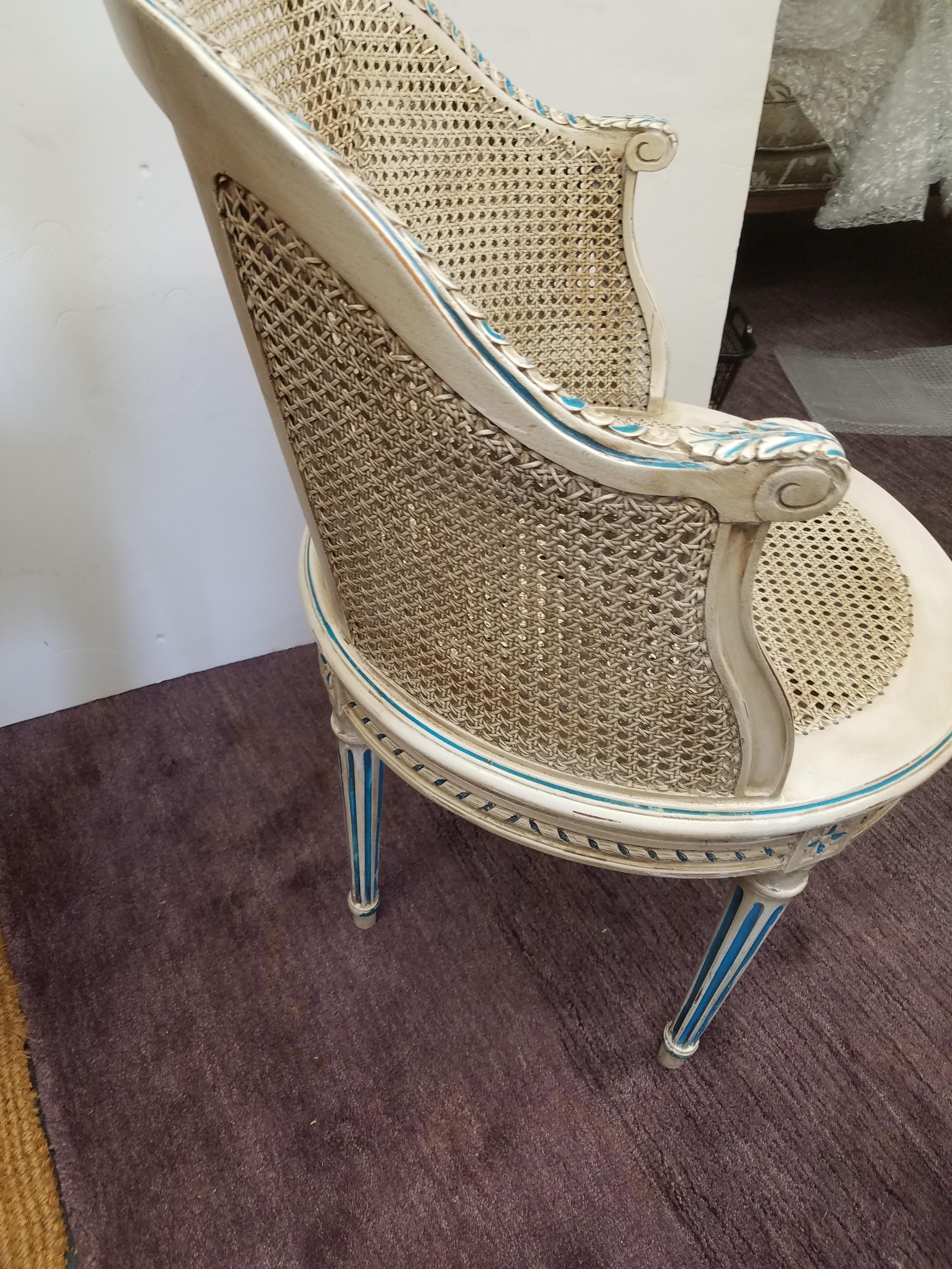 A carved hardwood Louis s swivel chair painted in an cream and blue finish. The rounded back with caned seat and arm with round swivel seat. French, early 20th Century