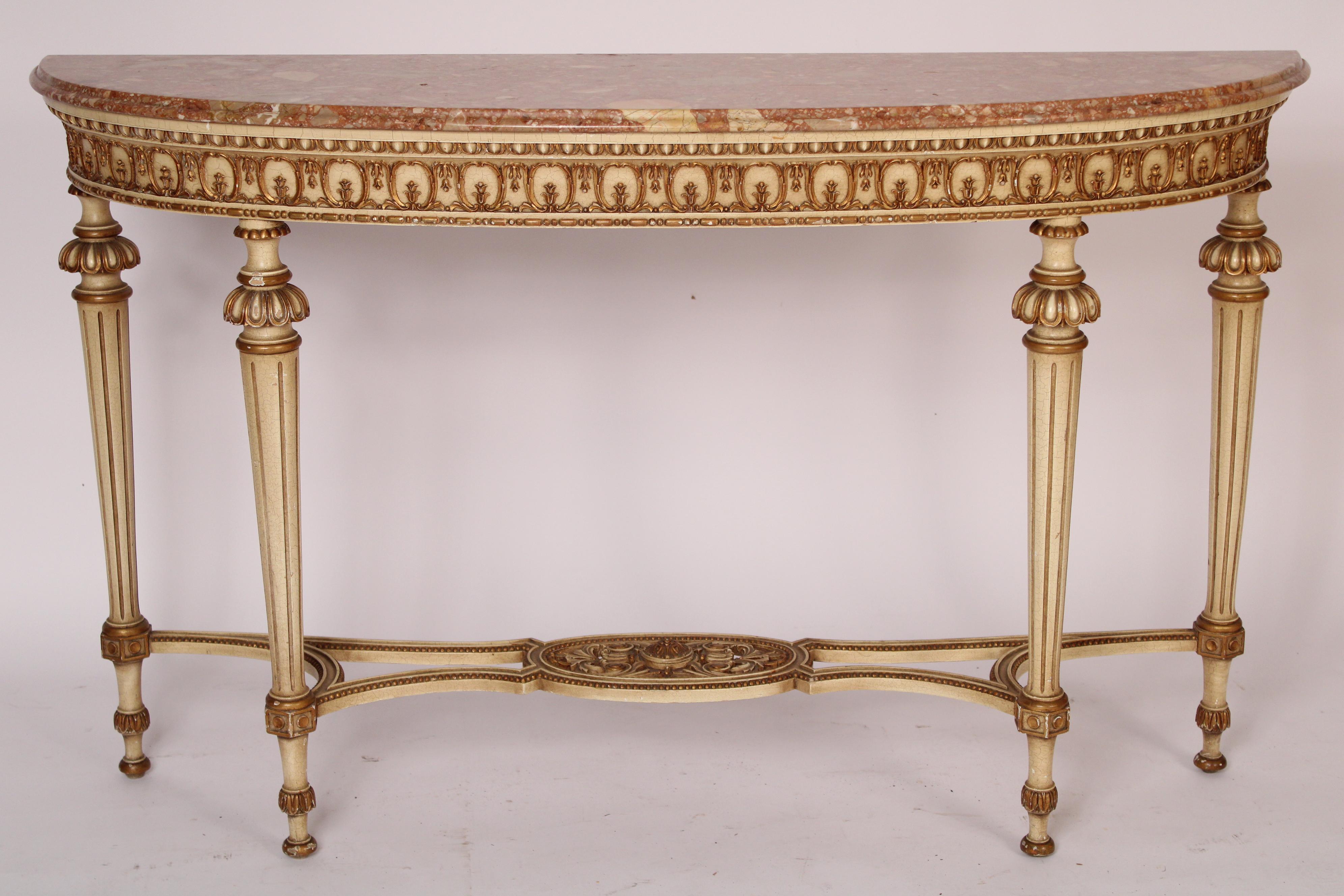 Louis XVI style painted and gilt decorated elongated demi lune marble top console table, circa 1960's. With an elongated demi lune marble top with ogee edge, a frieze with egg and dart motif and cartouche and bellflower design, resting on turned