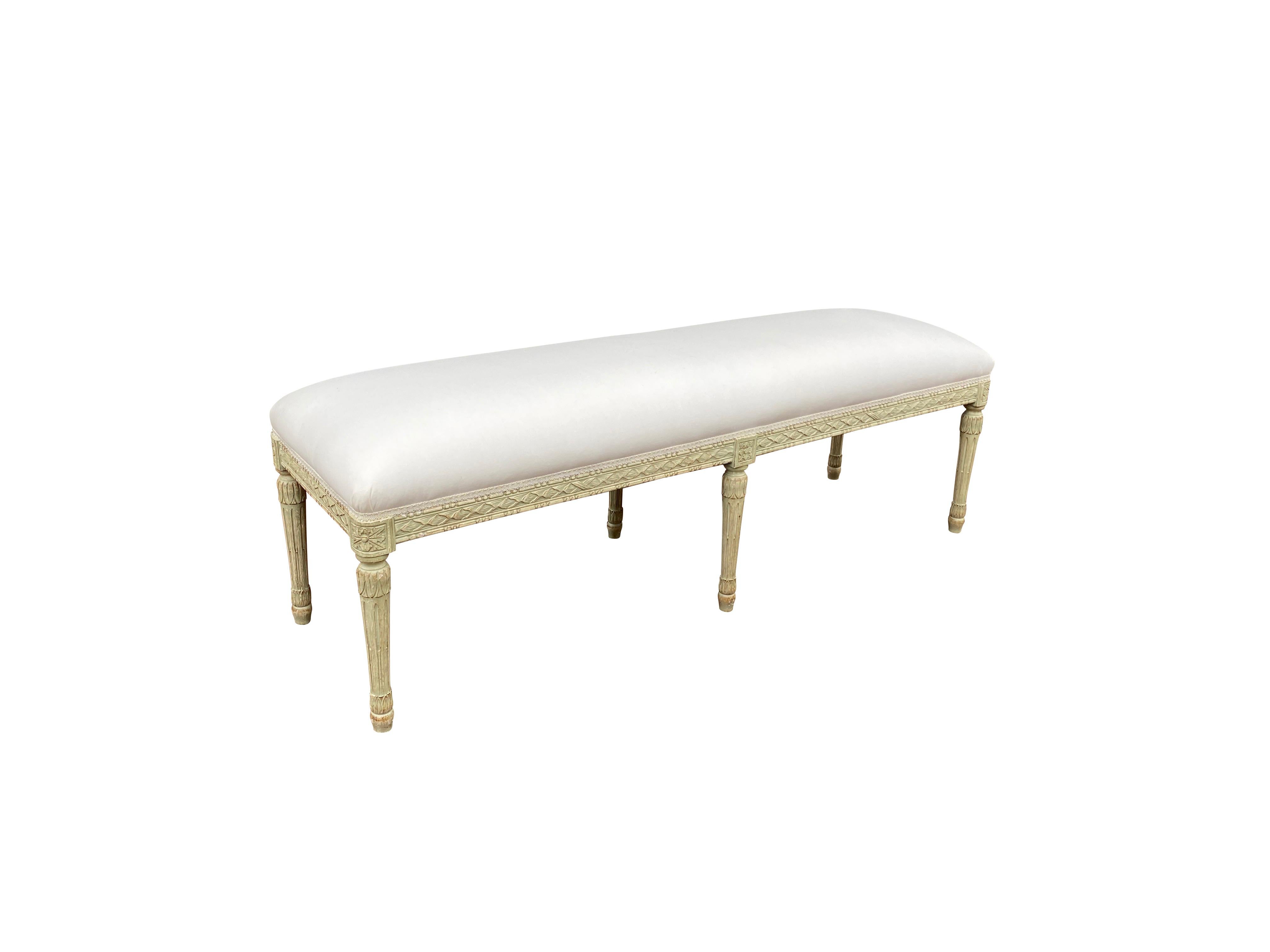 Rectangular upholstered seat and leaf carved frame and carved paterae at the top of the legs, circular fluted tapered legs.