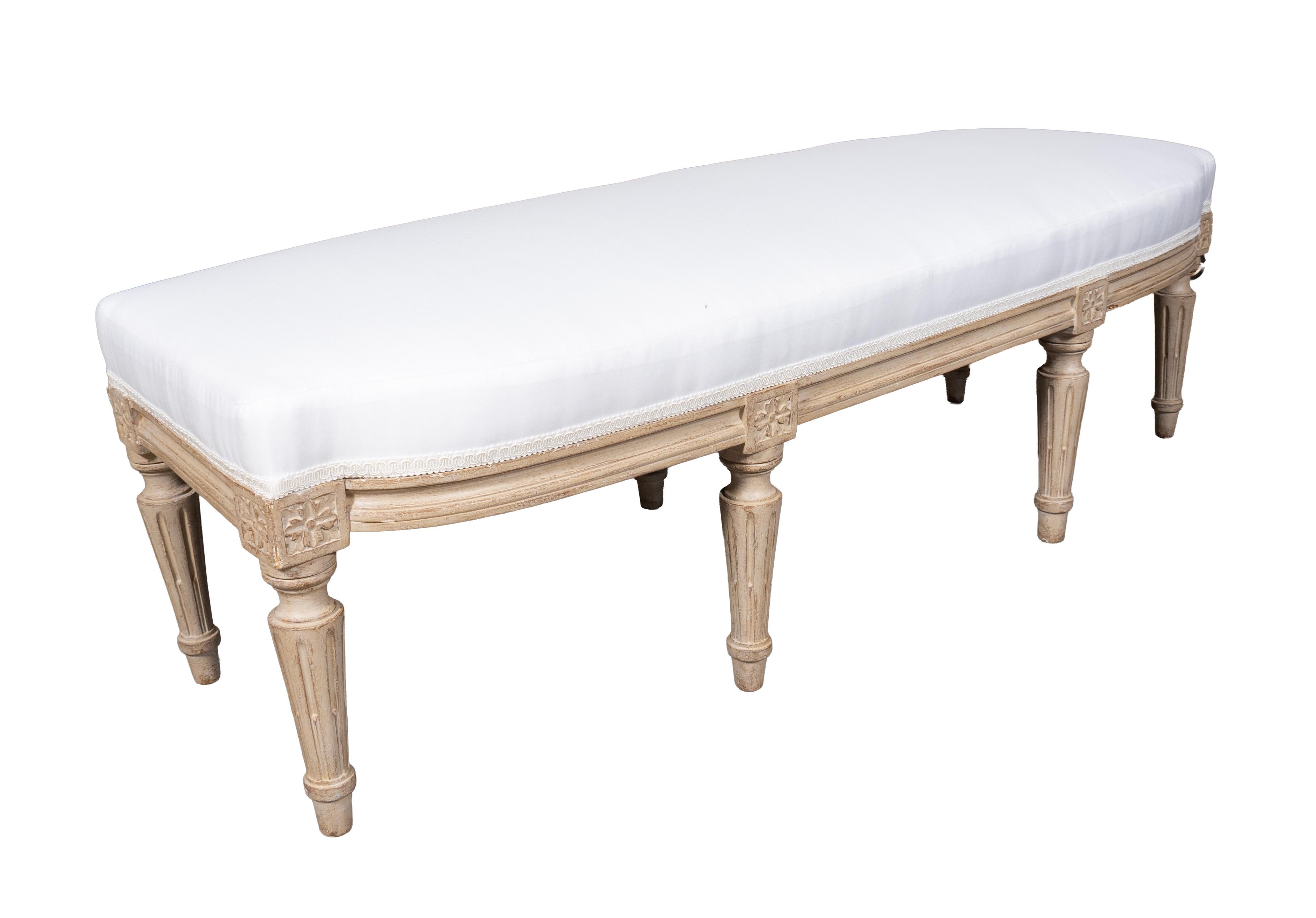 Rectangular bowed front newly upholstered in muslin. Circular tapered fluted legs.