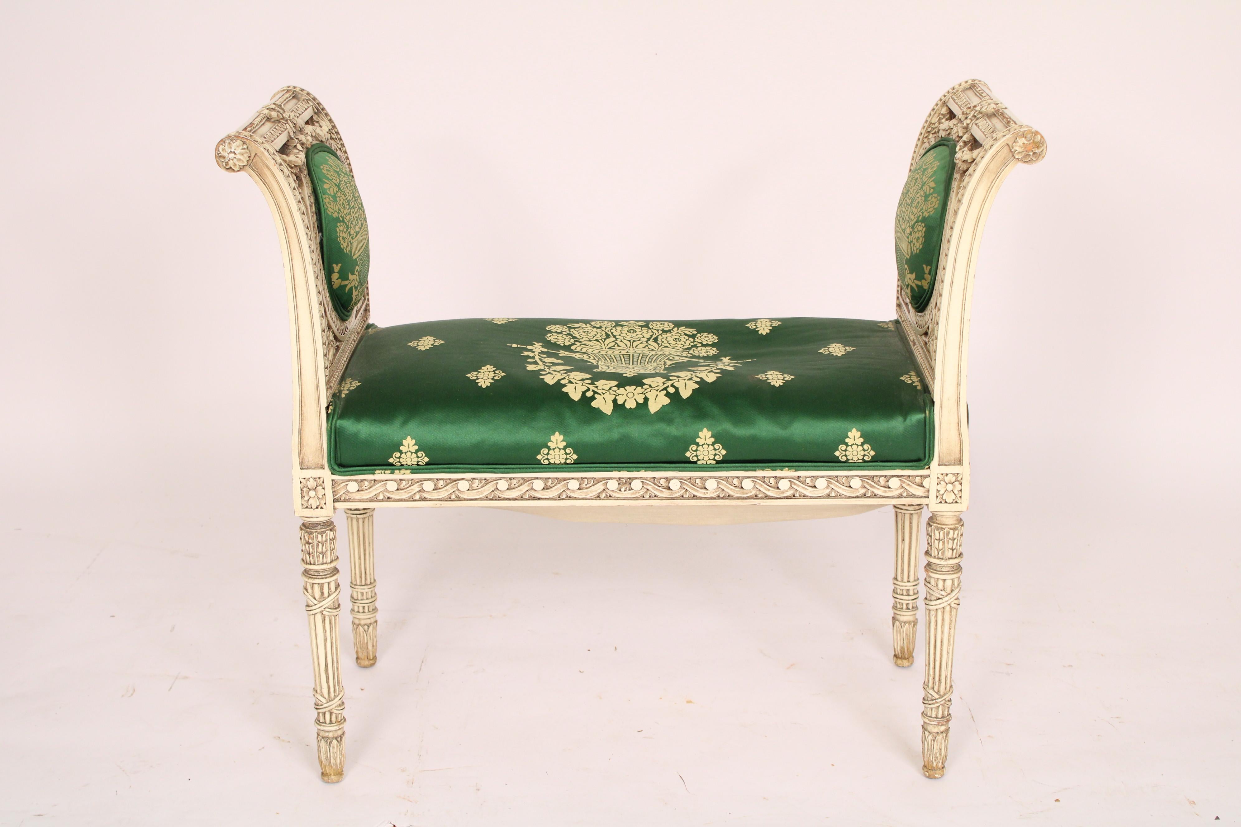 Louis XVI style painted bench, circa 1930s. The two arms carved with floral swags, gouilloche and floral designs, the green silk seat with neoclassic upholstery, resting on 4 reeded quiver style legs.