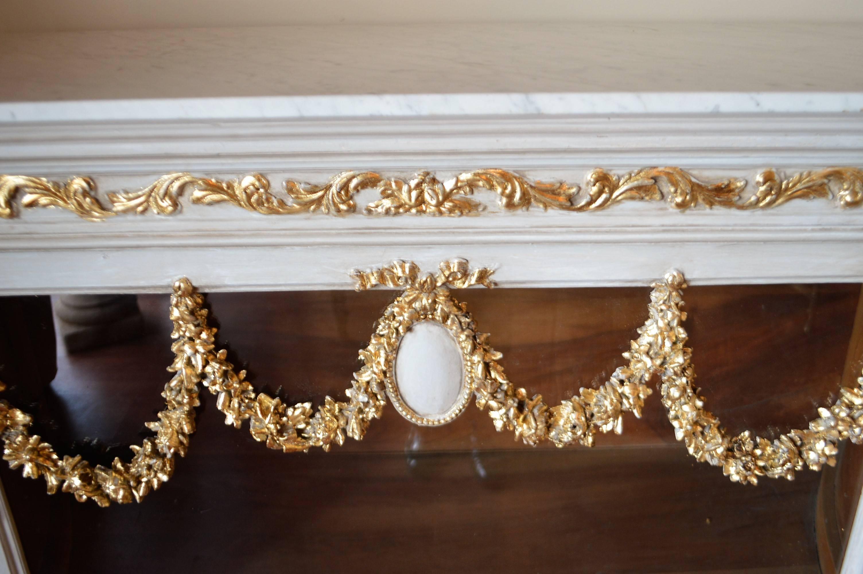 Unusual design painted cabinet with hand-carved swag and other decorative gilded elements. This cabinet would make a great bar.