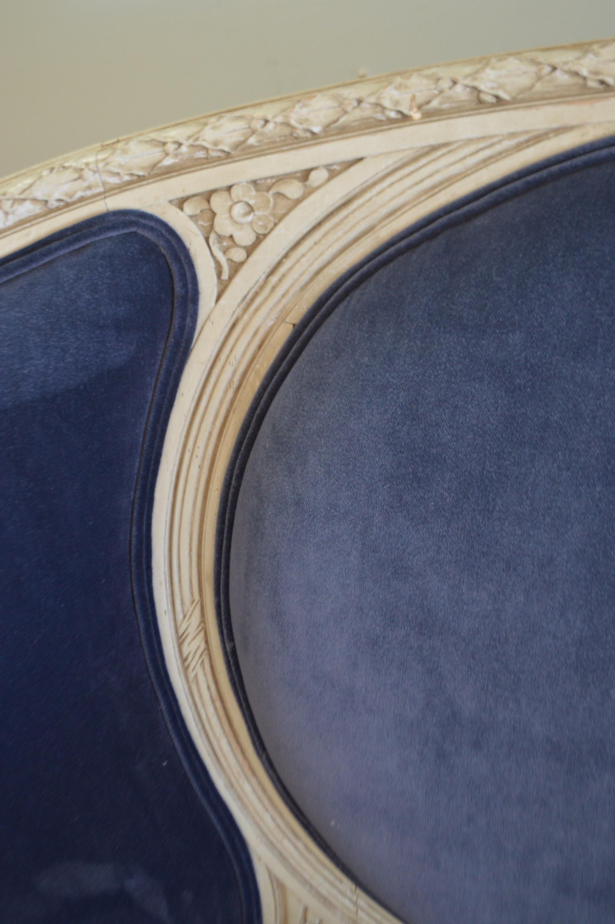 Louis XVI style canape from France, circa 1920 with the original grey painted frame. Elegant with its curved sides, hand-carved details of roses and bow the top.
It has been newly upholstered with a rich blue velvet, the seat cushion is a mixture