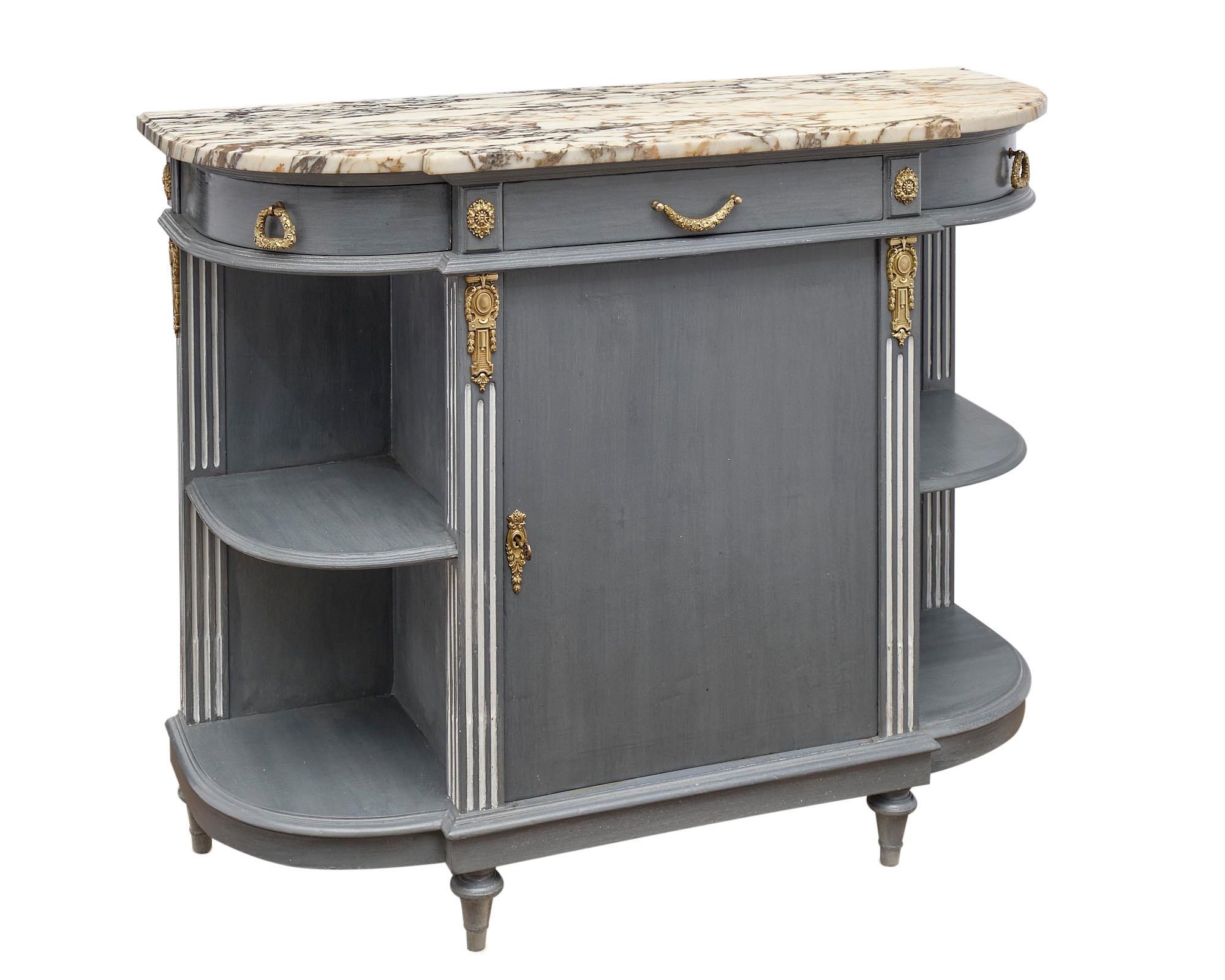 Louis XVI style painted demilune buffet in a “trianon” gray with white accents in the fluting and finely cast gilt bronze hardware. There are three dovetailed drawers above open shelving on the sides and a central door. The sideboard is topped with