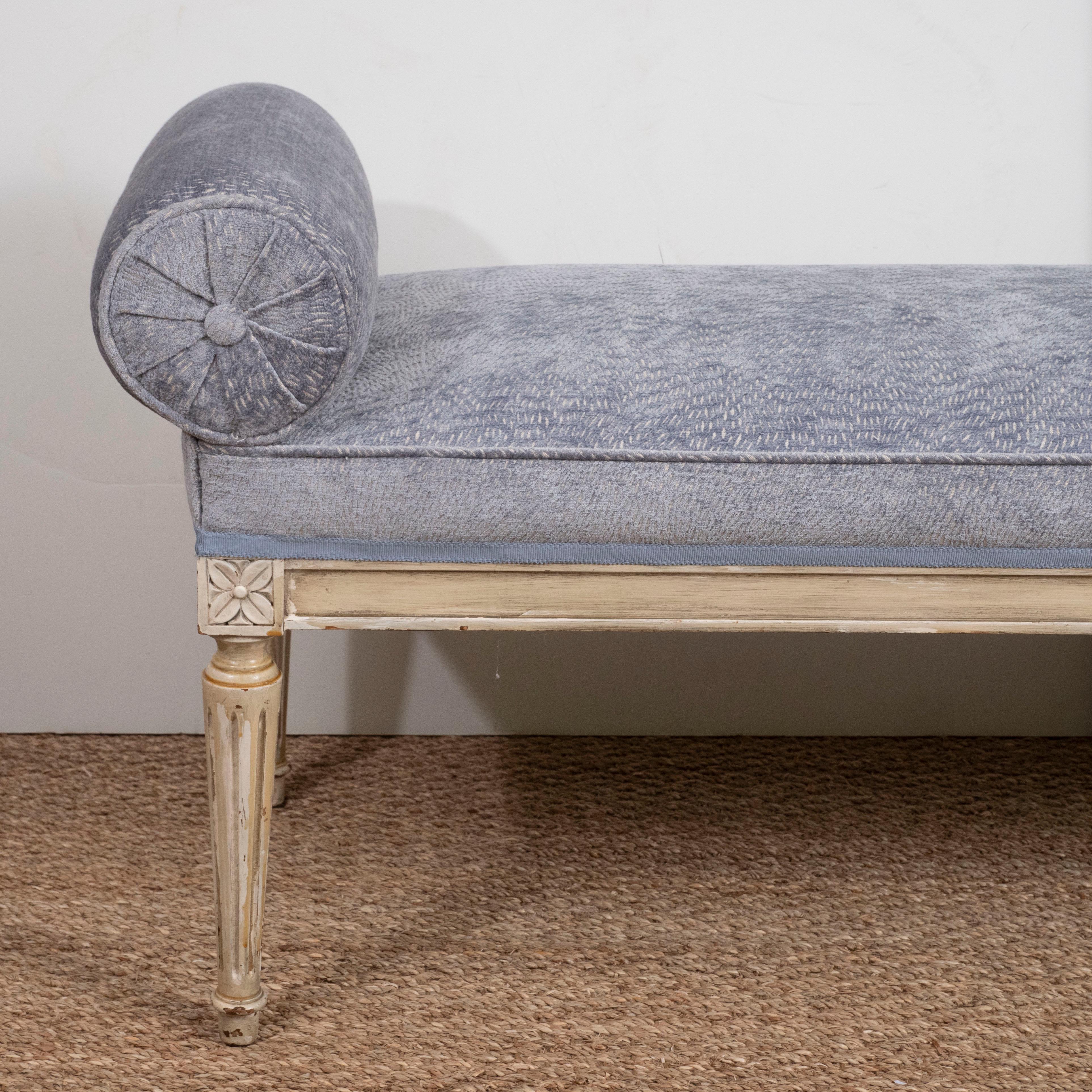 A Louis XVI style painted long bench with carved legs, including a reupholstered seat and side arms in a soft blue with subtle design. Perfect for the foot of a bed!