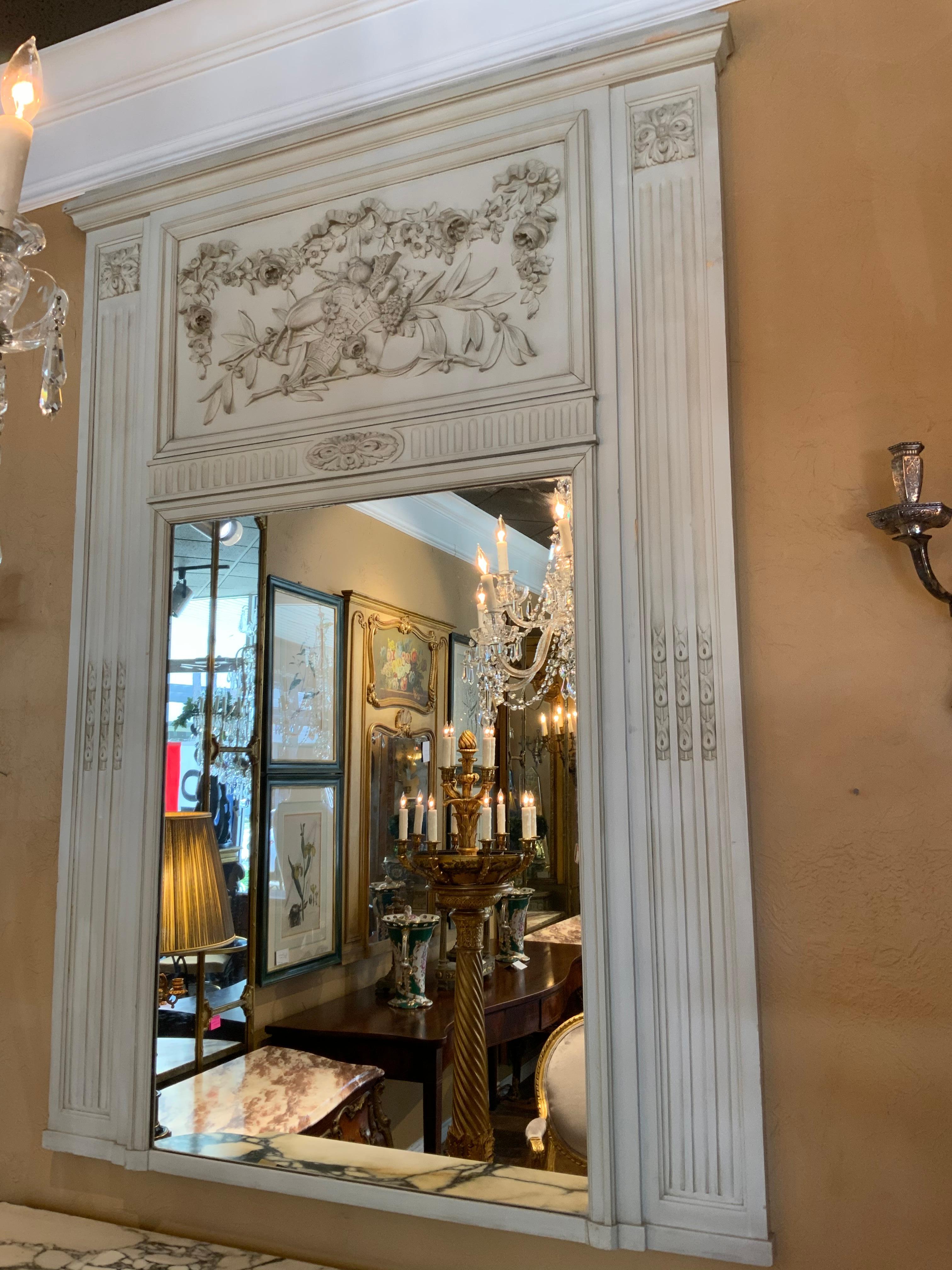 French painted trumeau mirror, 19th century. Moldedcornice over applied carved frieze of cornucopia
Musical instruments and floral garlands, fluted and foliate carved side panels, encasing a flat
Mirror plate.
