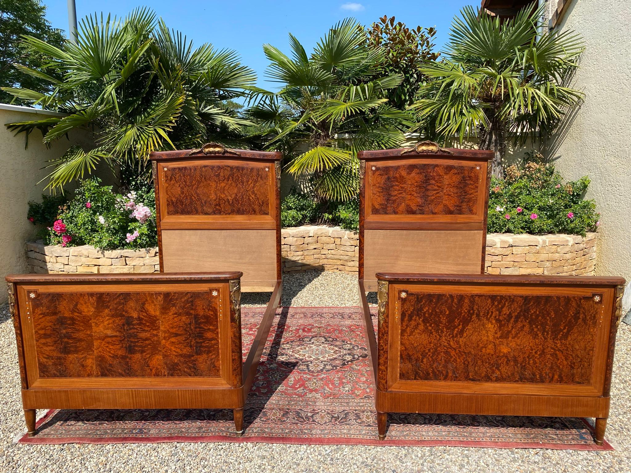 Pair of Louis XVI style beds in amboyna burl adorned with gilded bronzes. These beds date from the 1920s and are in good condition.