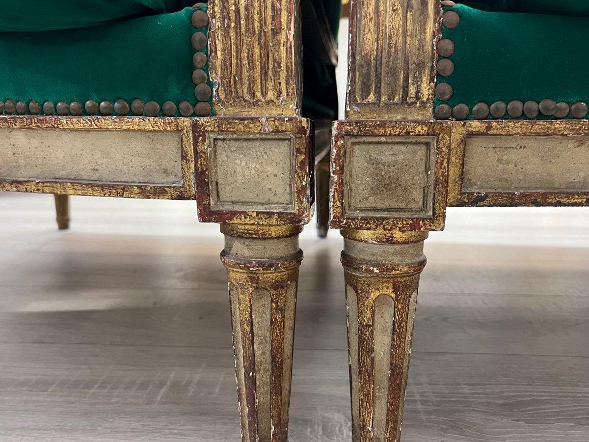 A unique pair of wooden two-seaters with a charming period patina, supported by four sturdy, fluted, and ringed tapered legs. They feature simply moulded crossbars connected by diamond-adorned blocks. Dating back to the Louis XVI era, these chairs