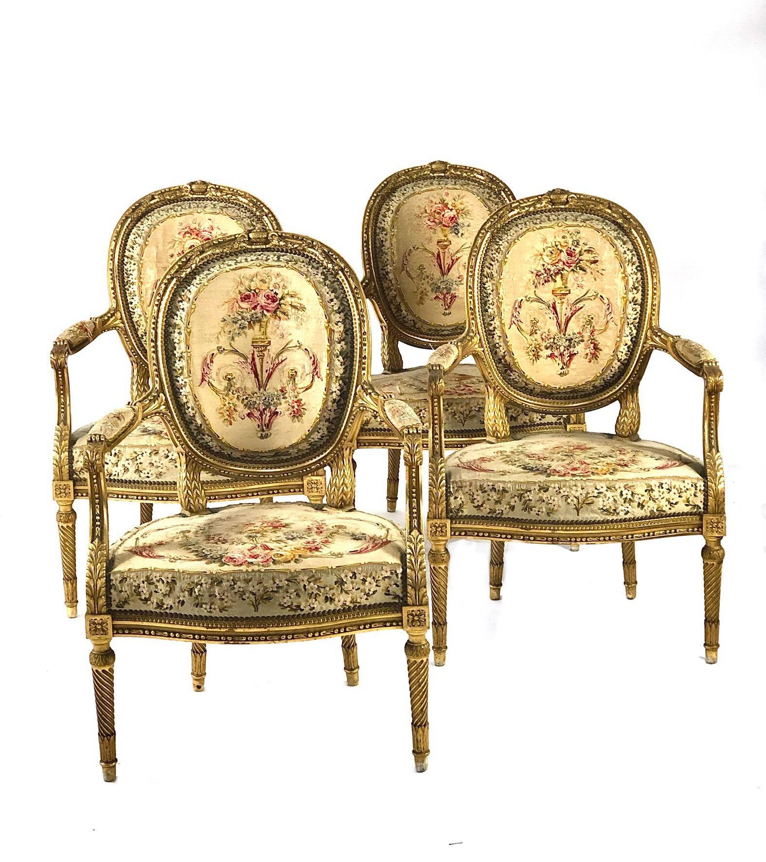 An exquisite suite of giltwood living room furniture in the Louis XVI style, comprising a two-seater sofa and four matching armchairs. Elegantly carved and upholstered, this fine set exhibits richly carved motifs throughout, as well as attractively