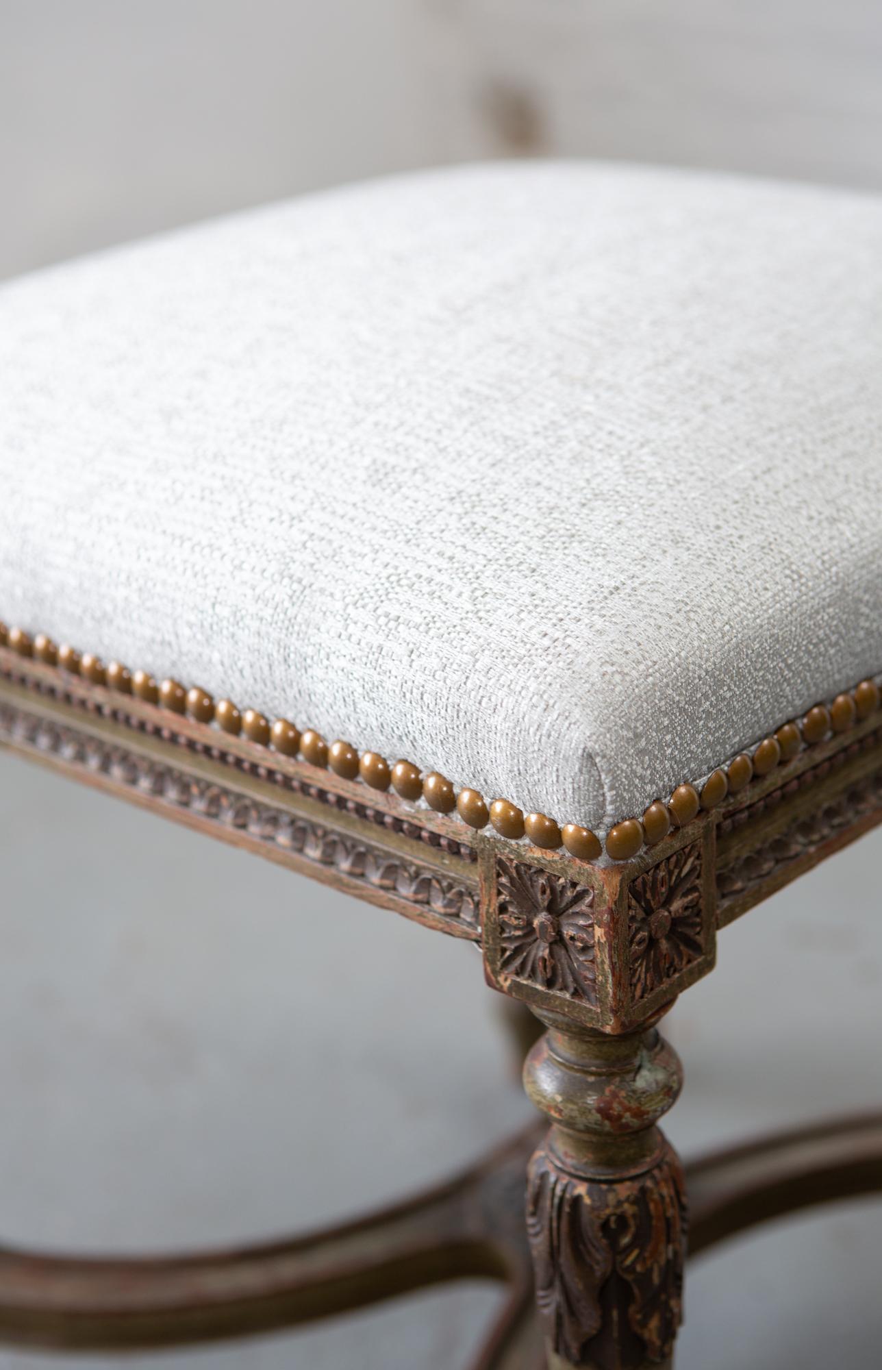 Tabouret en bois sculpté de style Louis XVI, parfaitement vieilli, avec un coussin nouvellement tapissé et des détails de feuilles sur les pieds. Merveilleux détails sculptés partout.