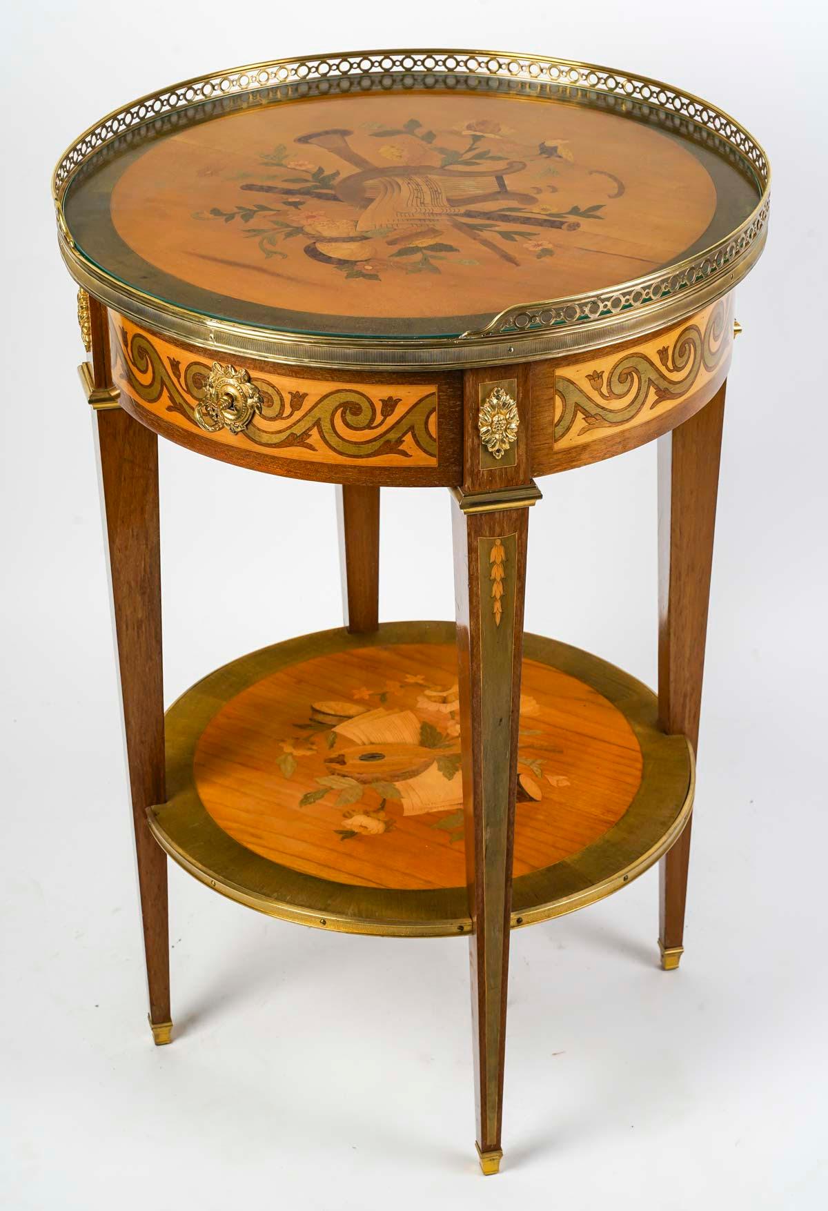 Louis XVI style pedestal table, 19th Century, Napoleon III period.

Veneered pedestal table, top covered with Louis XVI style glass, precious wood marquetry with music and bird decorations, gilt bronze mount, early 20th century.  
h: 75.5cm, d: 51cm